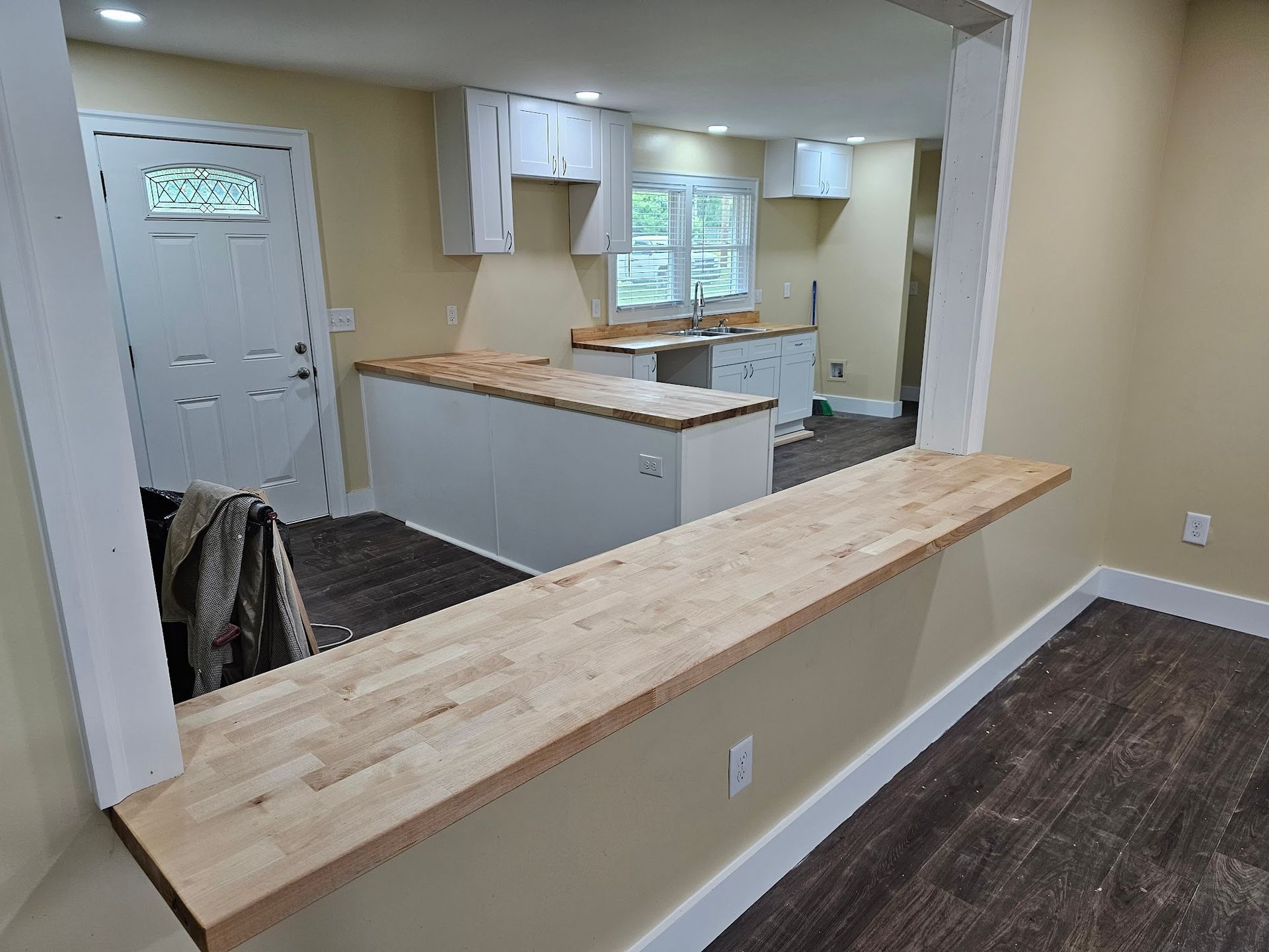A kitchen with a wooden counter top and white cabinets.