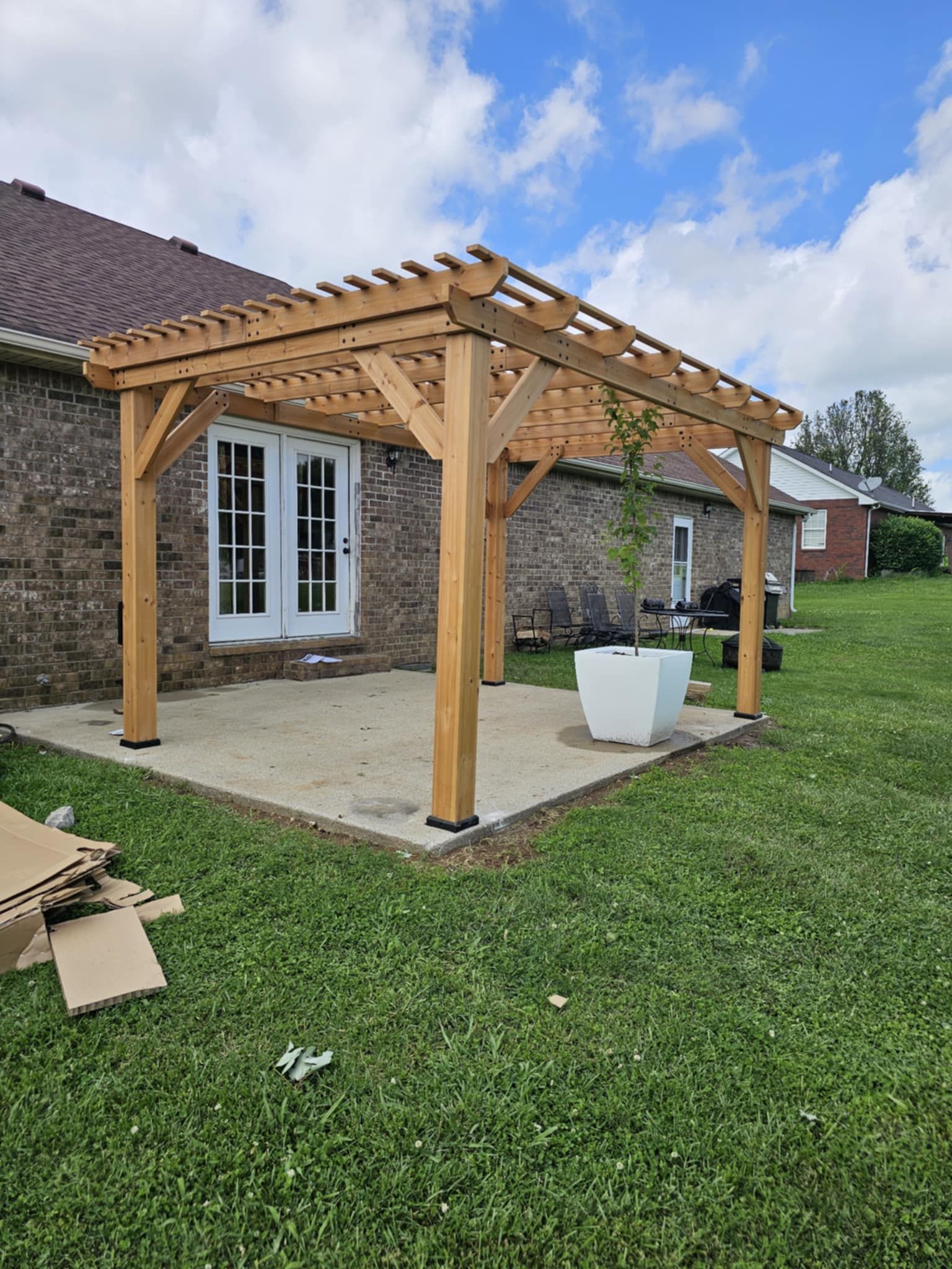 A wooden pergola is sitting in the backyard of a house.