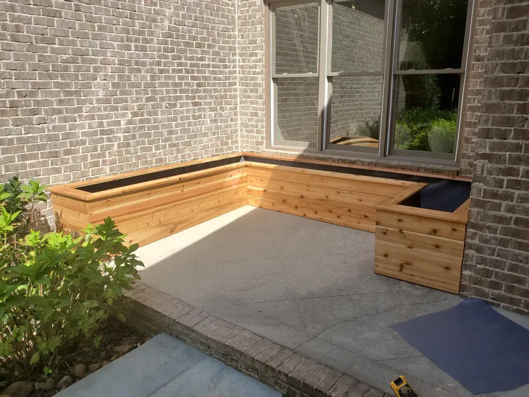 A wooden bench is sitting on the side of a brick building.