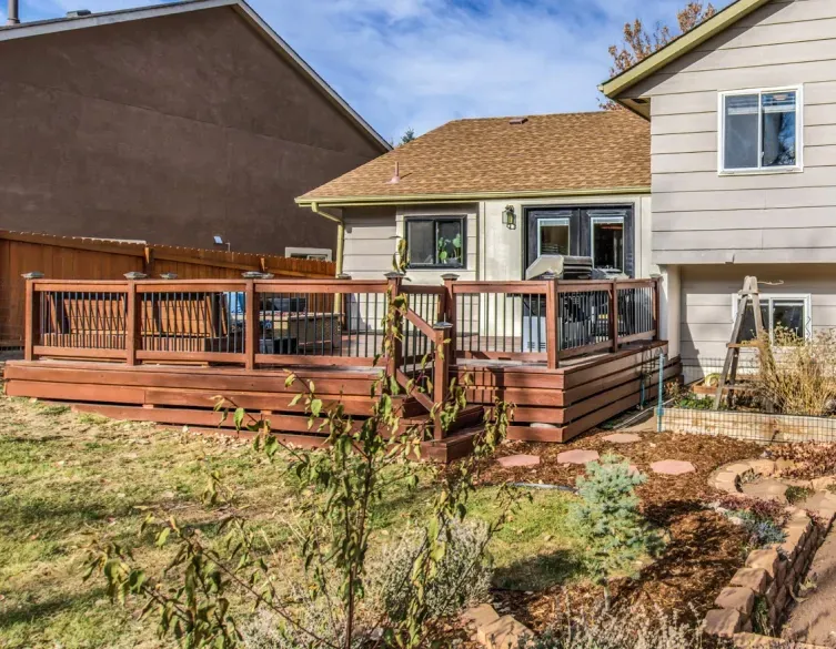A large wooden deck is in the backyard of a house.