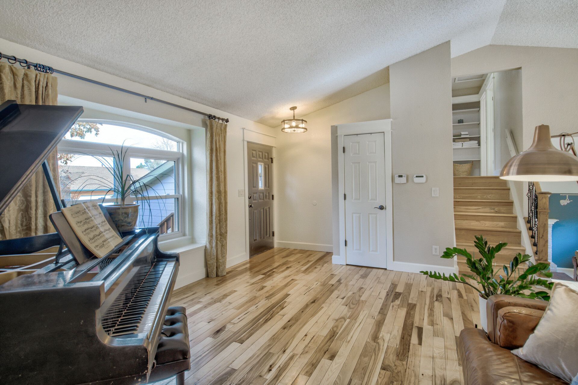 A living room with a piano , couch , and stairs.