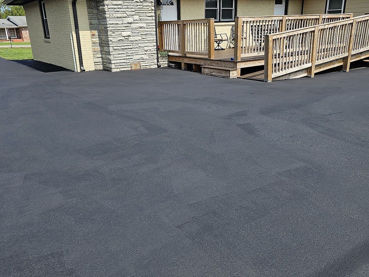 A driveway leading to a house with a ramp and a deck.