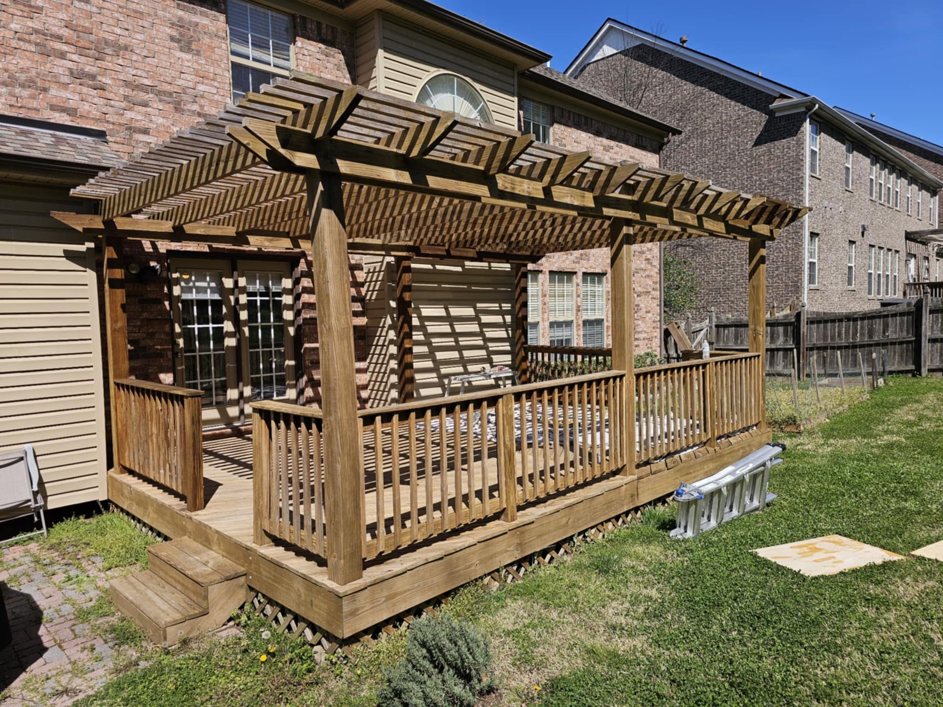 A wooden deck with a pergola in the backyard of a house.