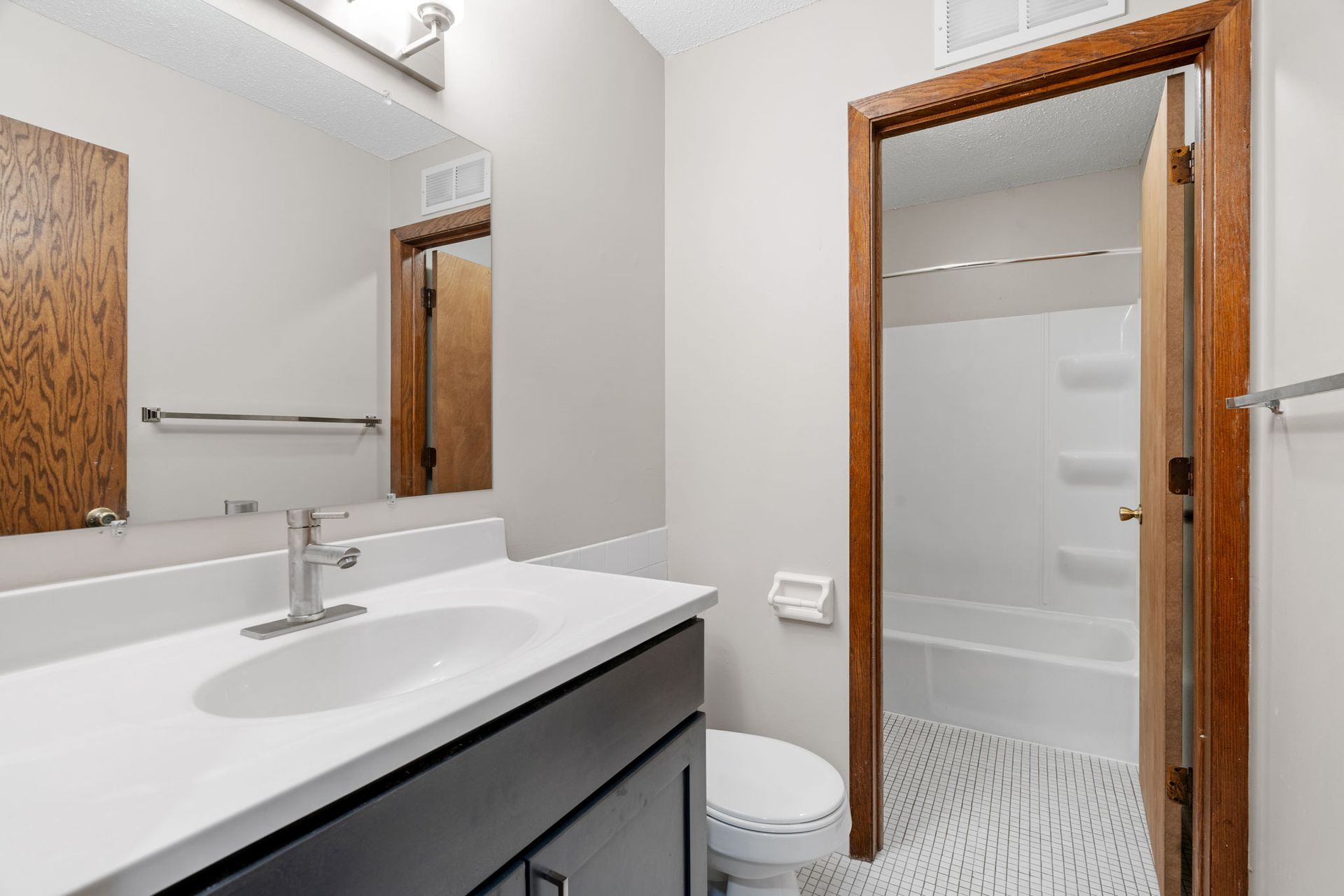 A bathroom with a sink , toilet , shower and mirror.