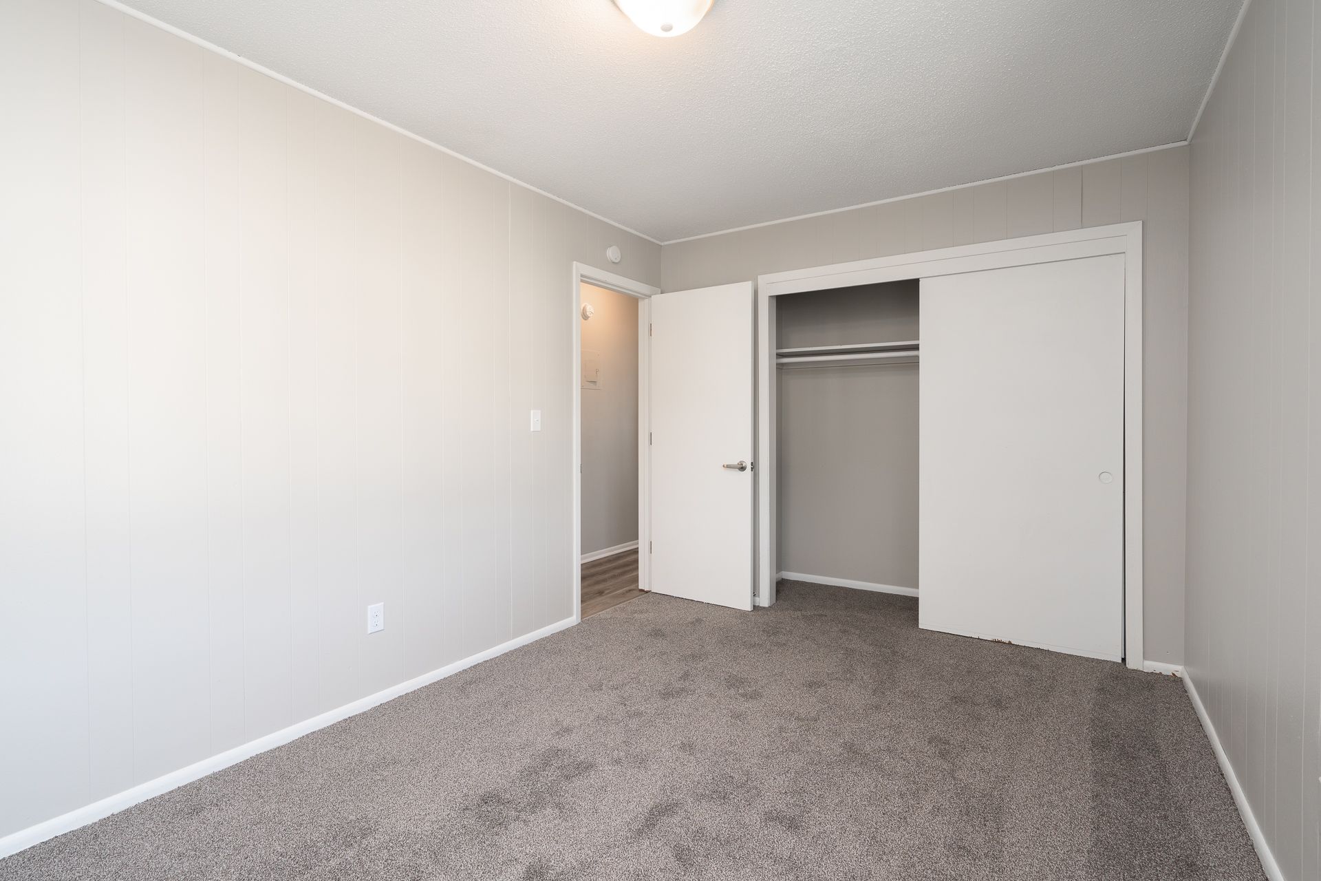 An empty bedroom with a closet and a carpeted floor.