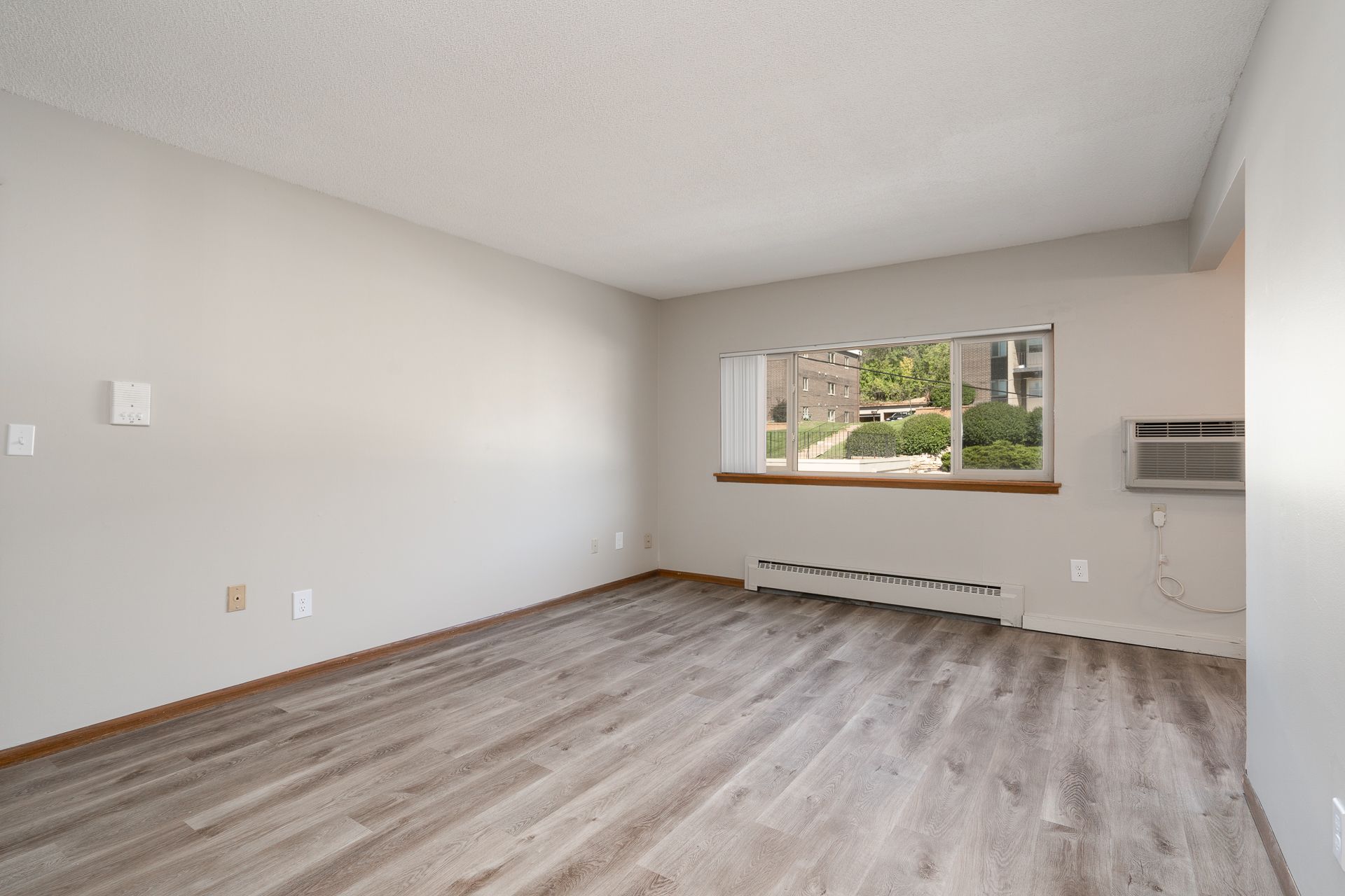 An empty living room with hardwood floors and a window.
