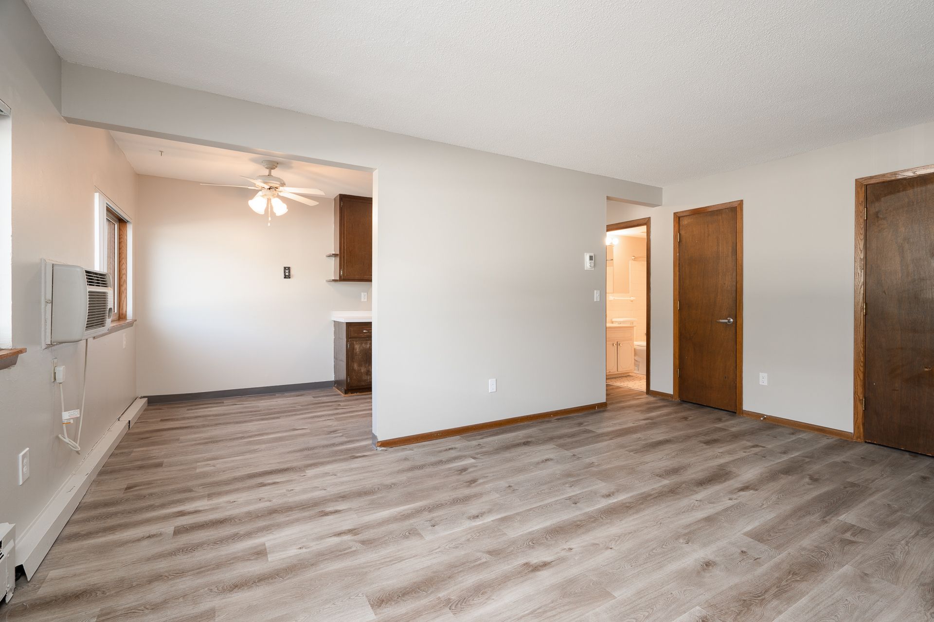 An empty living room with hardwood floors and a ceiling fan.