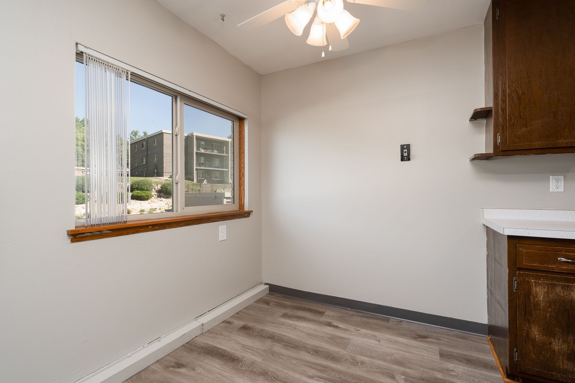 An empty room with a window and a ceiling fan.