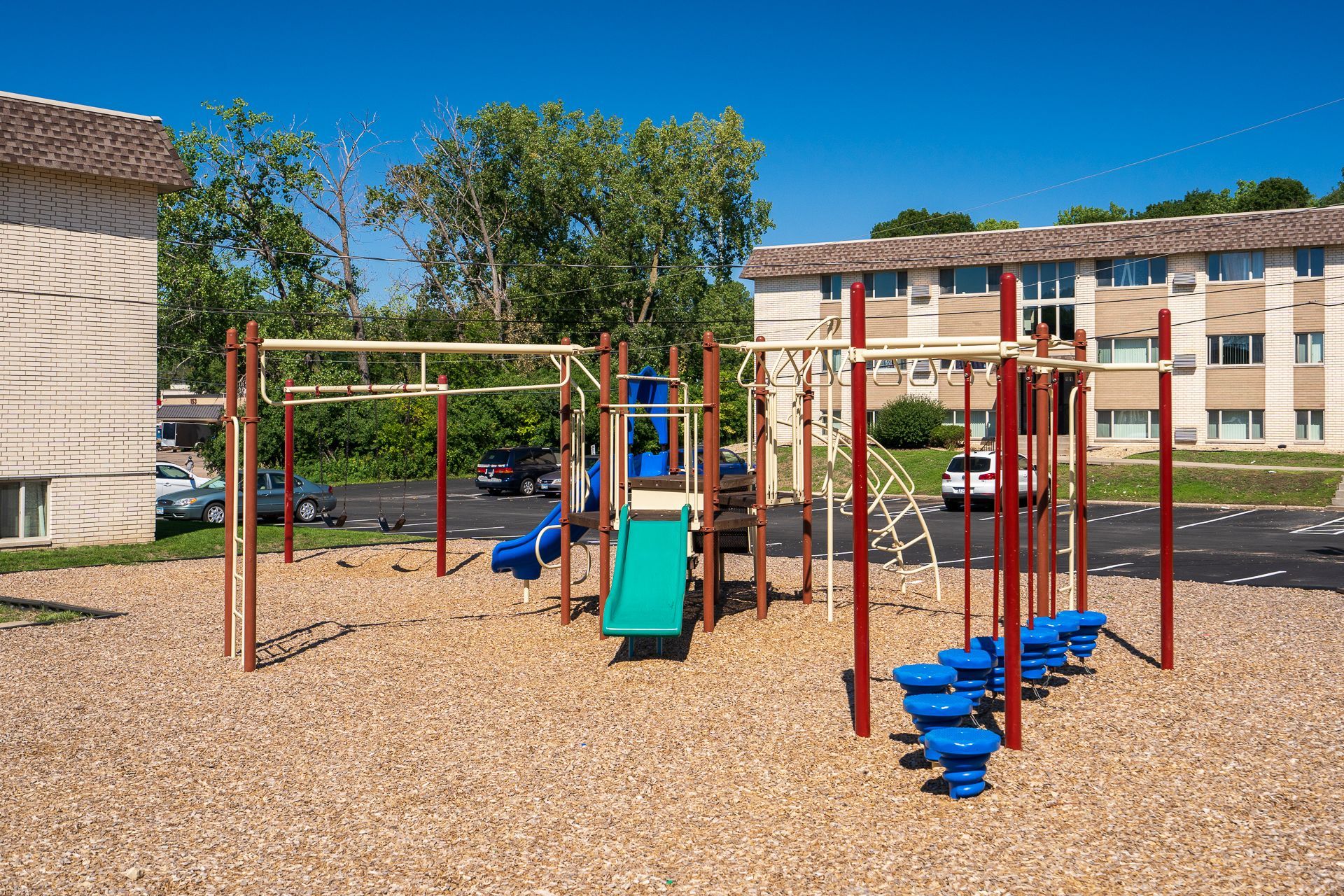 A playground with a slide and swings in front of a building.