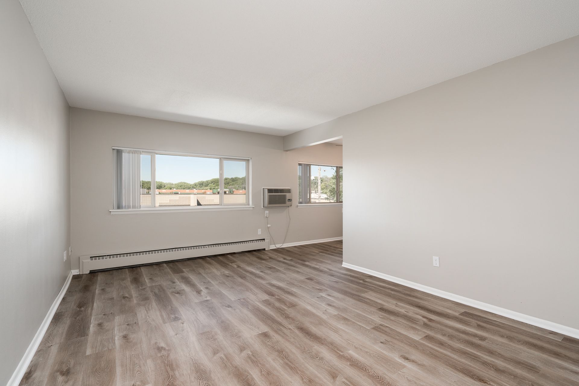 An empty living room with hardwood floors and a window.