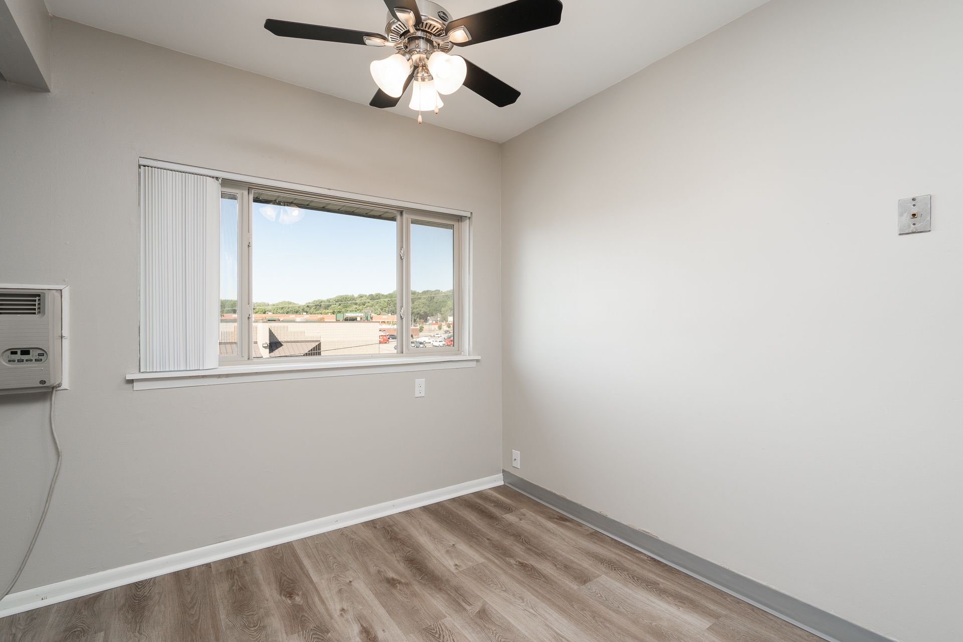 An empty room with a ceiling fan and a window.