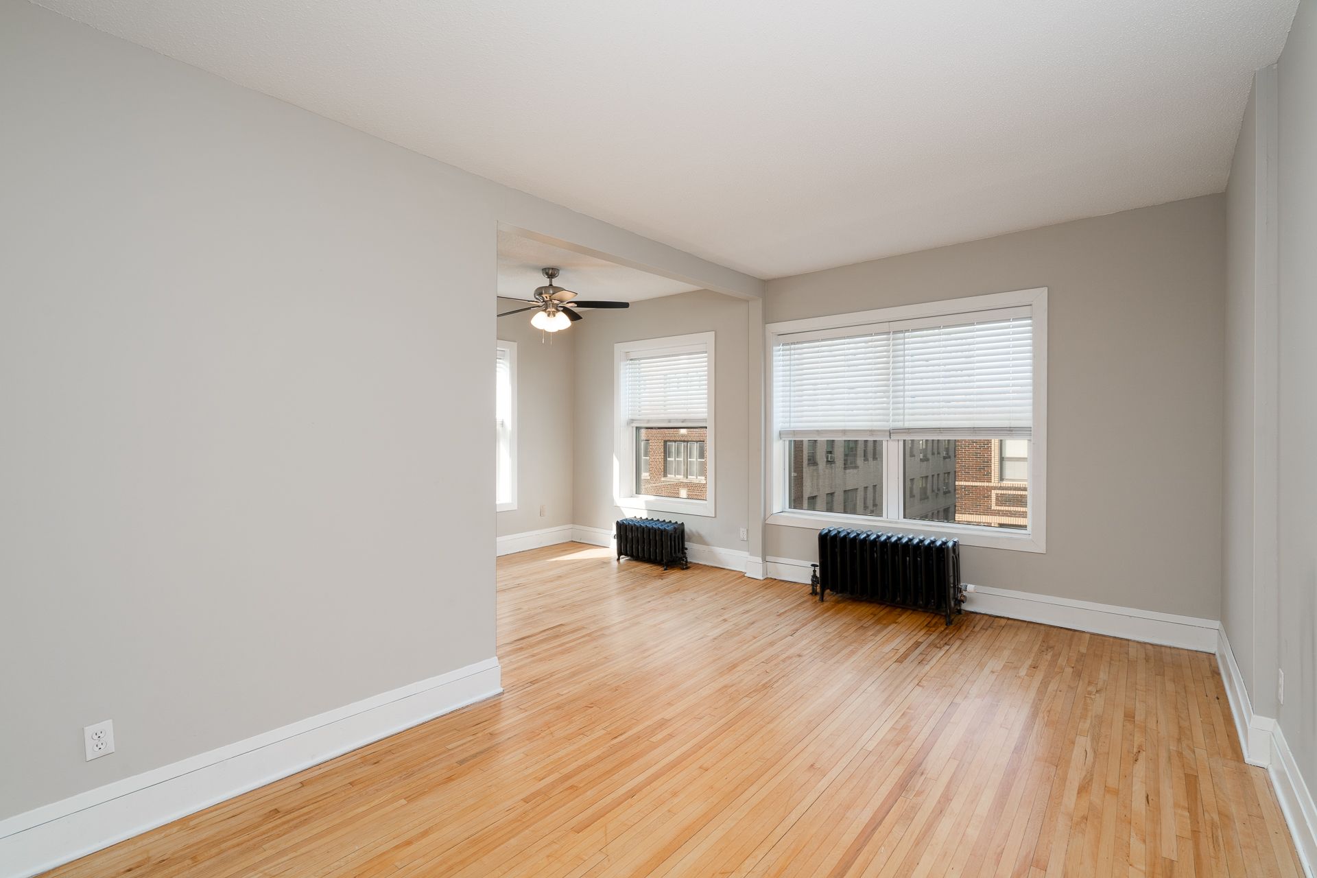 An empty living room with hardwood floors and a ceiling fan.
