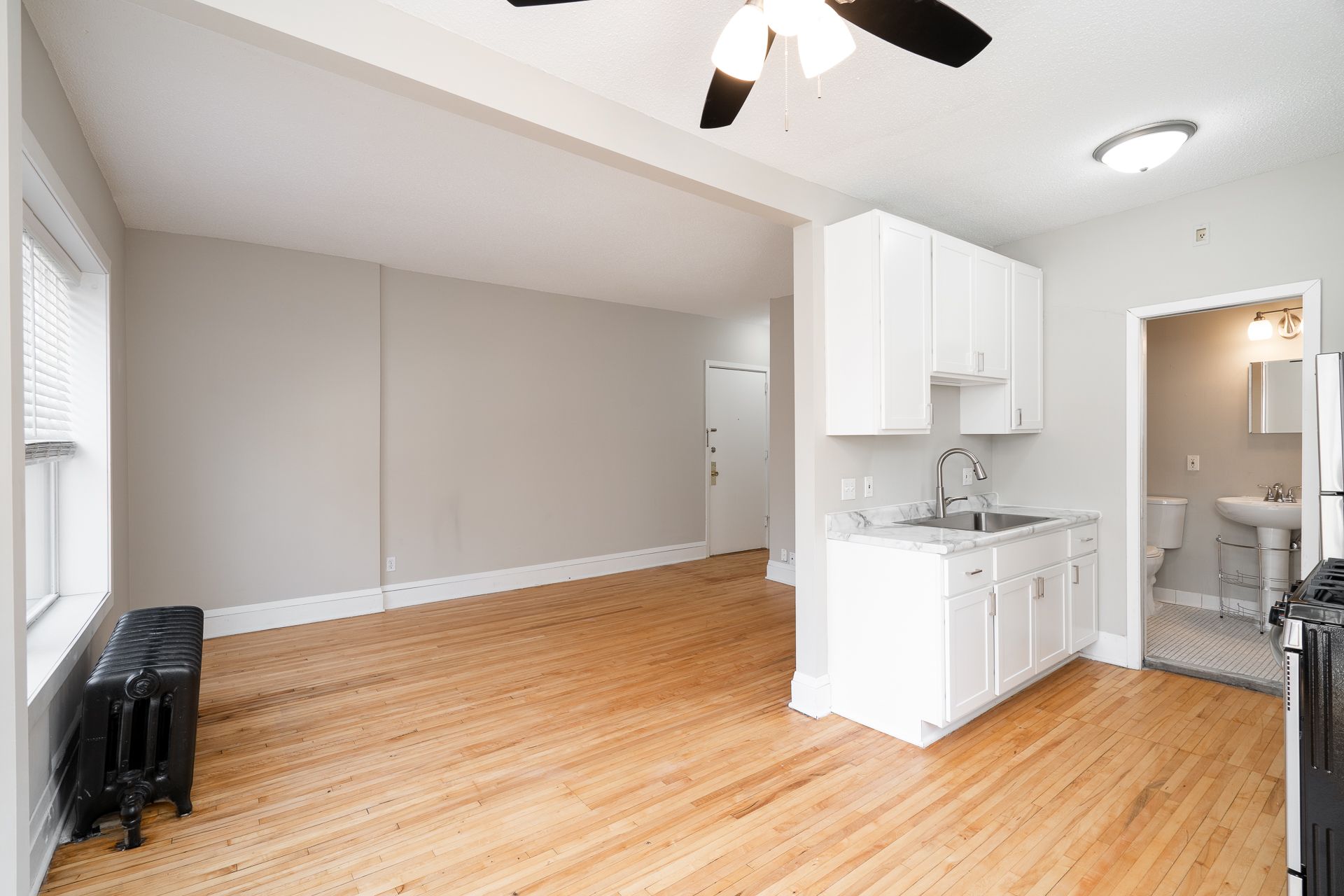 There is a ceiling fan in the kitchen and a sink in the living room.