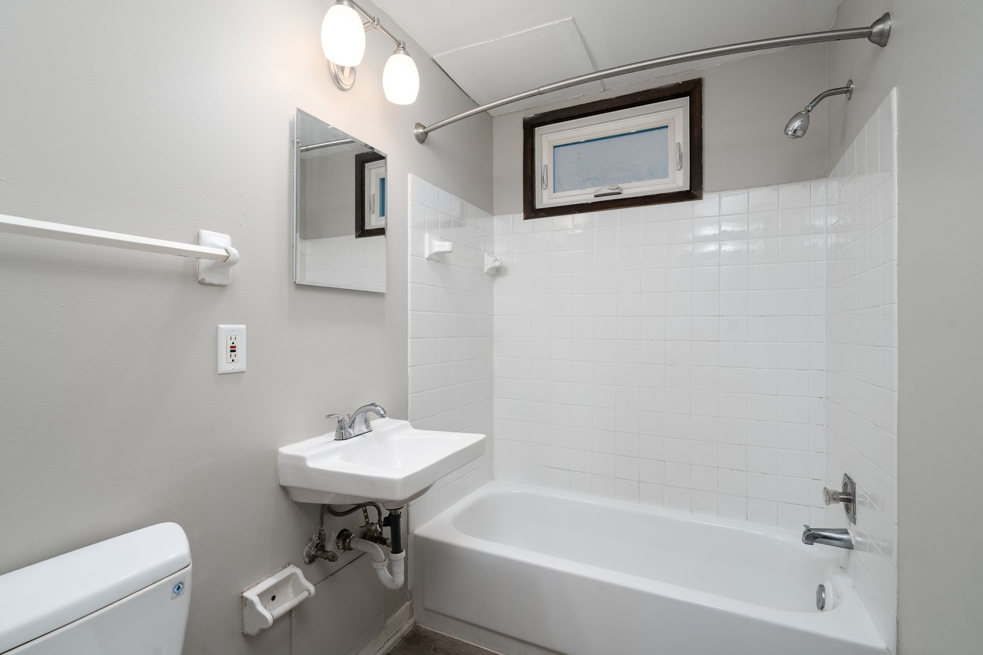 A bathroom with a toilet , sink , and bathtub.