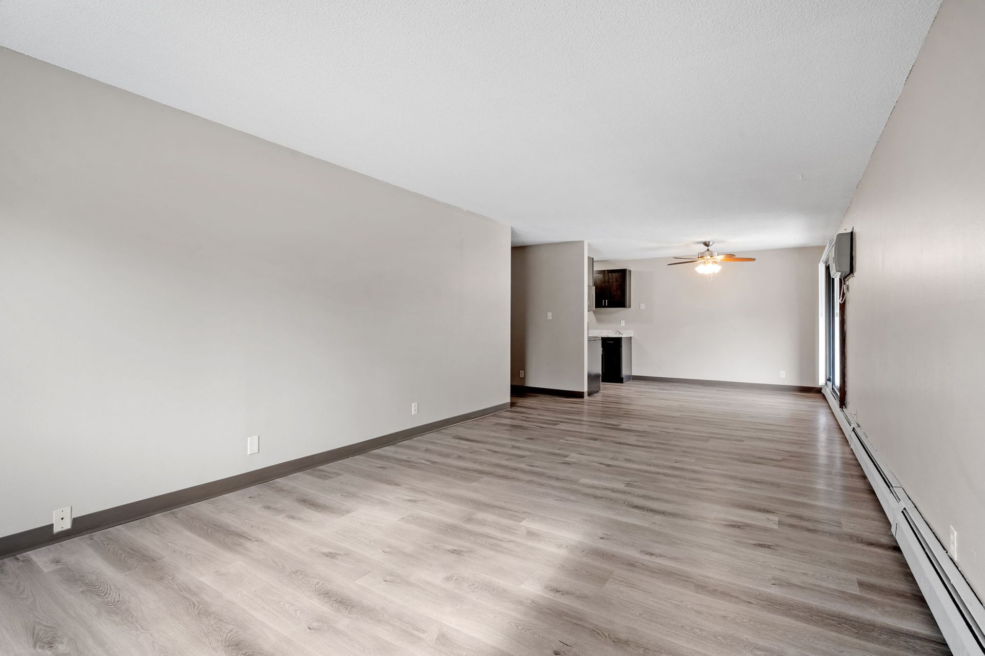 An empty living room with hardwood floors and a ceiling fan.