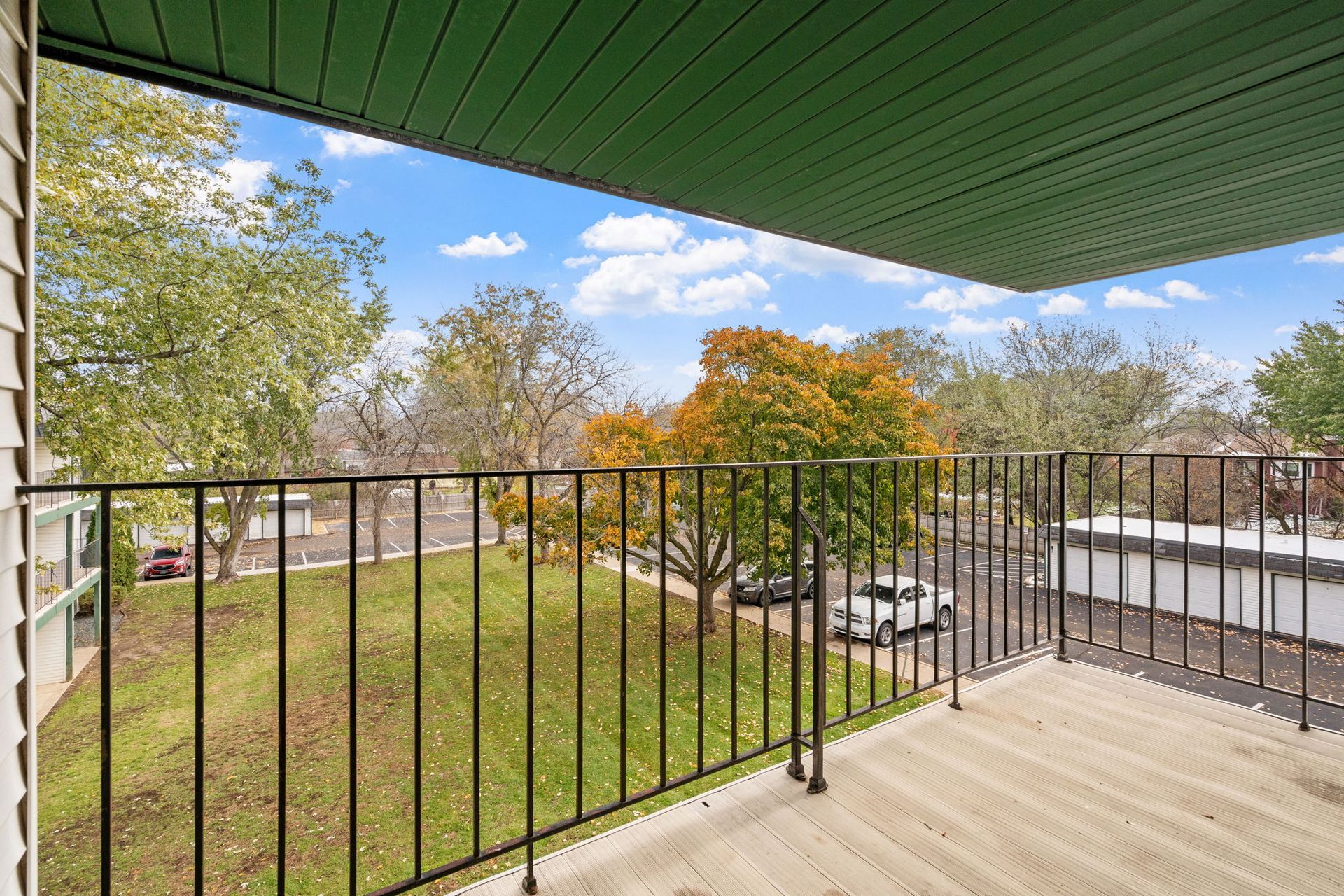 A balcony with a metal railing overlooking a lush green field.