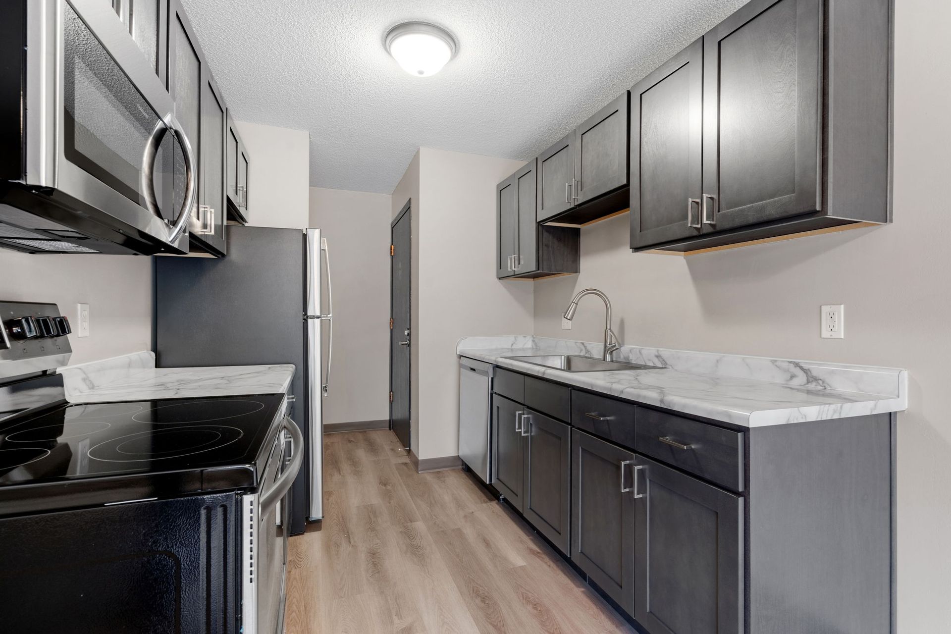 A kitchen with a stove , microwave , refrigerator , sink and cabinets.