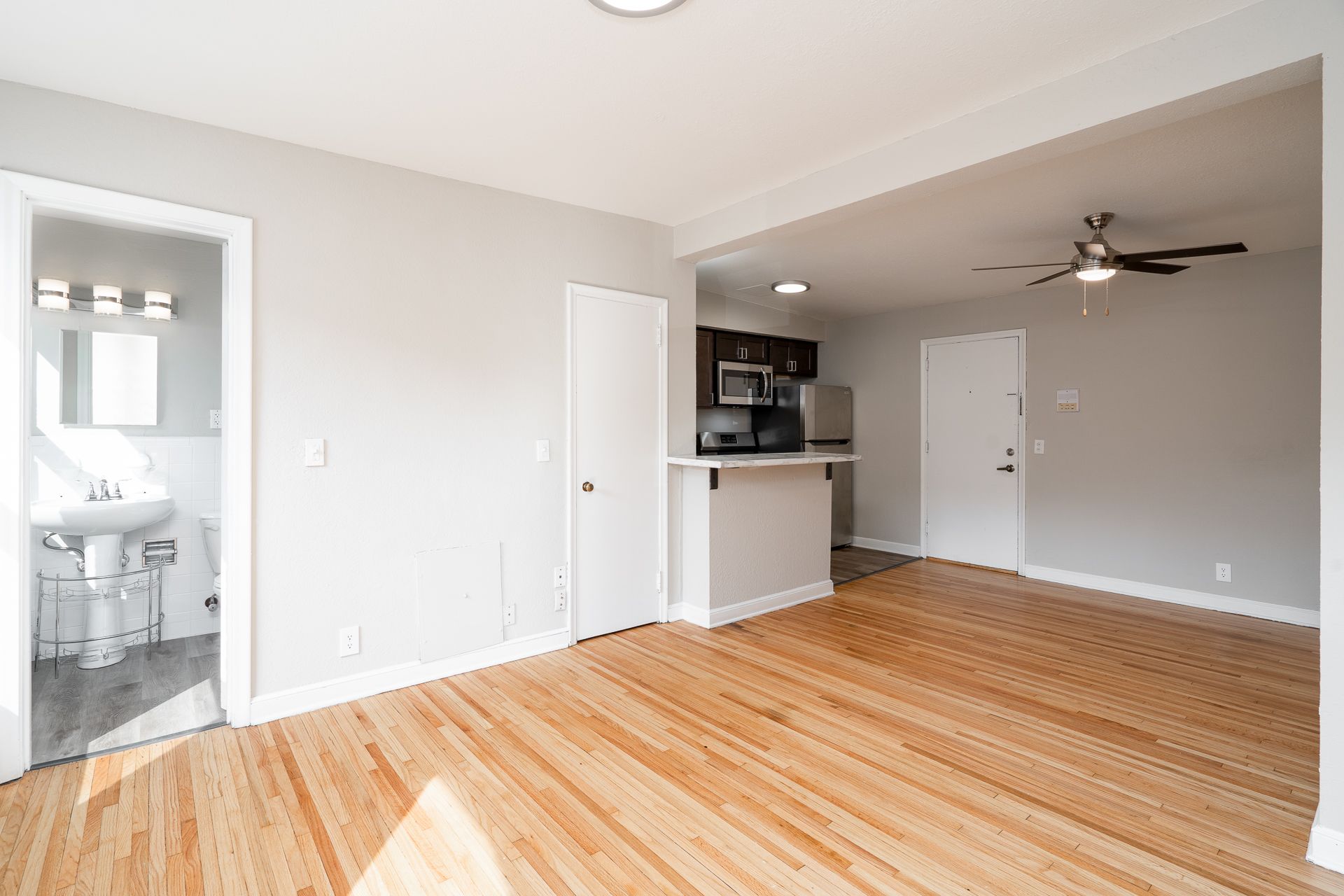 An empty living room with hardwood floors and a ceiling fan.