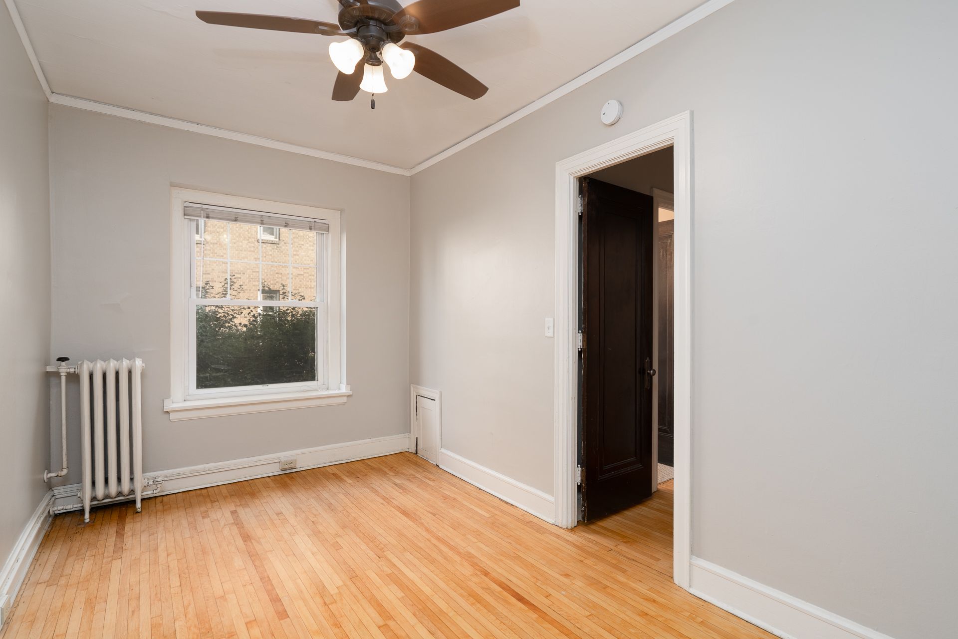 An empty room with a ceiling fan and a window.