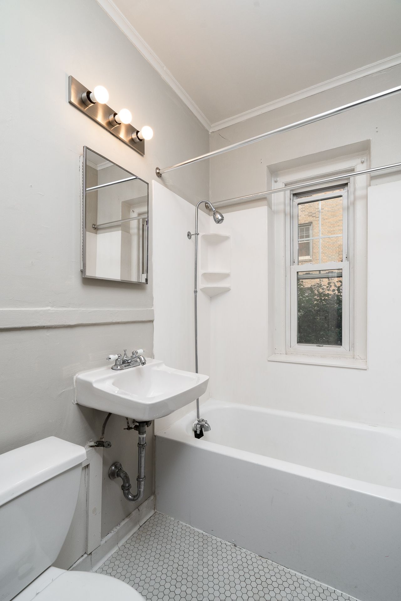 A bathroom with a sink , toilet , tub and mirror.