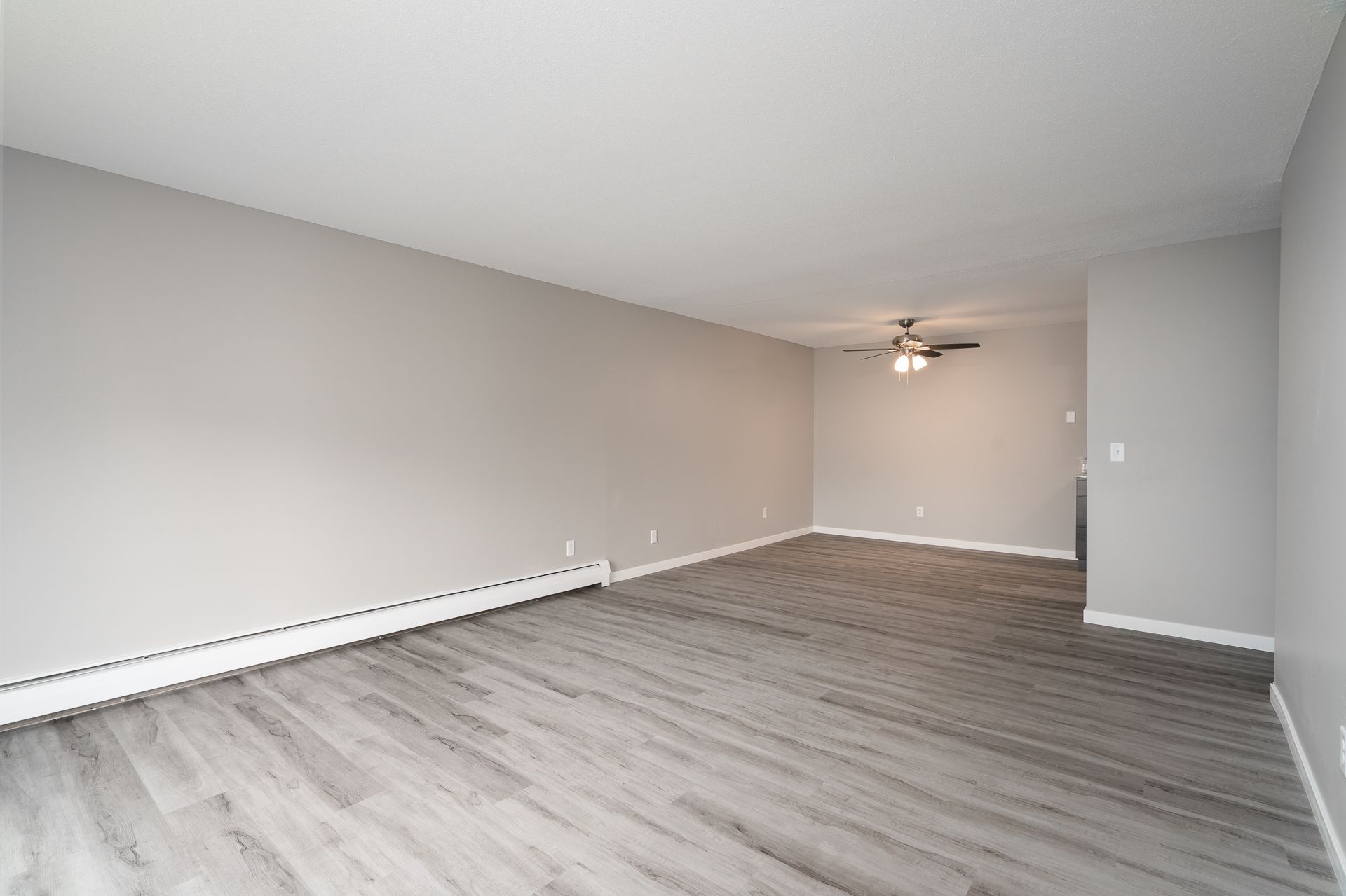 An empty living room with hardwood floors and a ceiling fan.