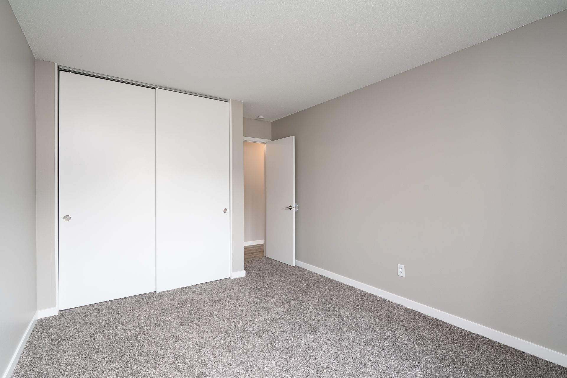 An empty bedroom with a carpeted floor and white walls.