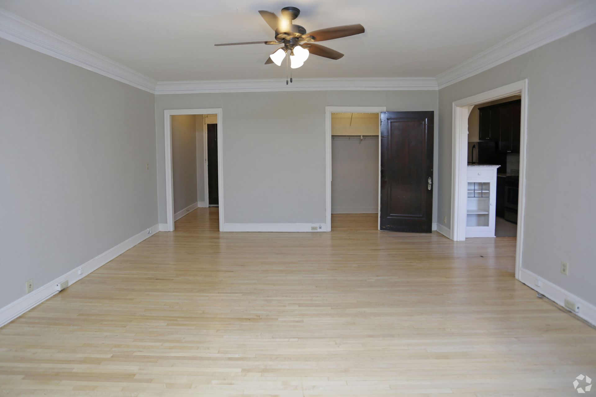 An empty living room with hardwood floors and a ceiling fan