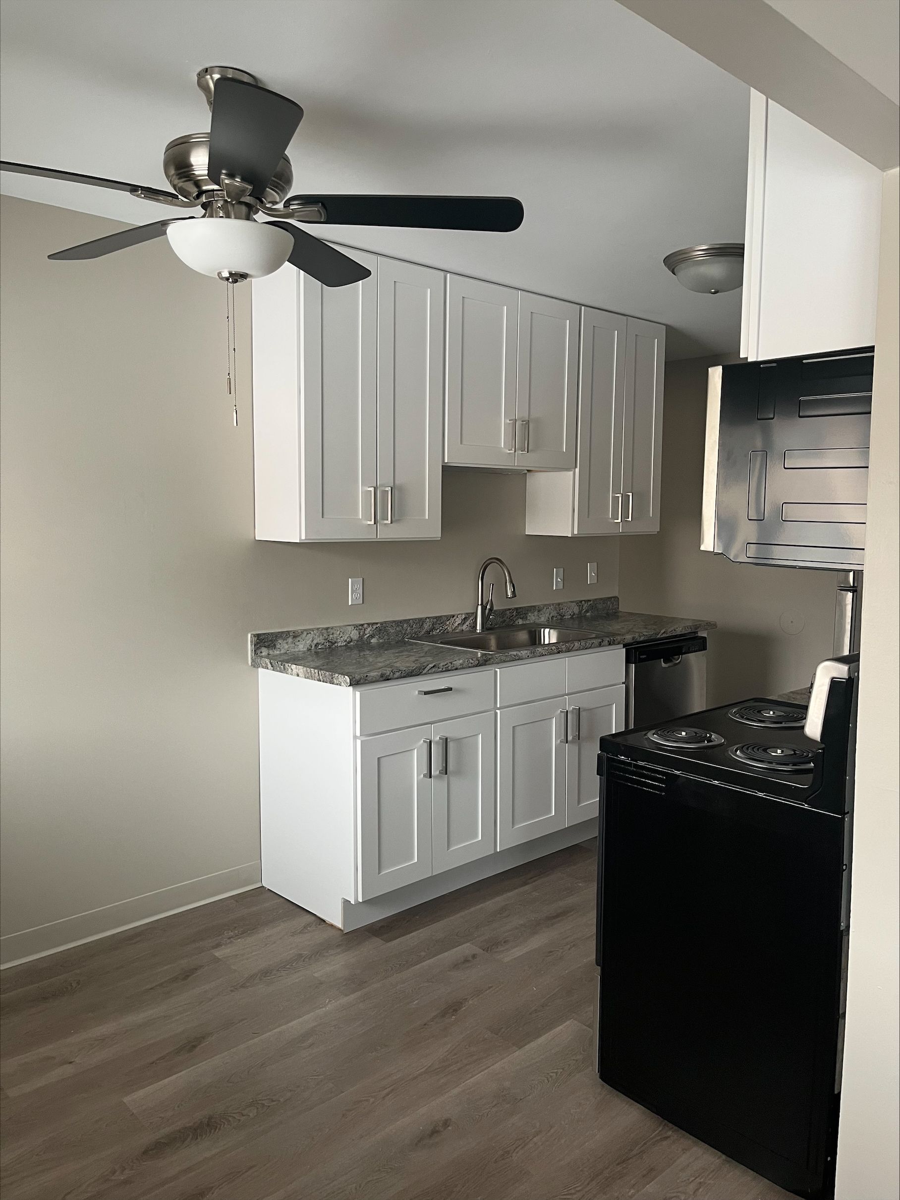 A kitchen with white cabinets and a ceiling fan