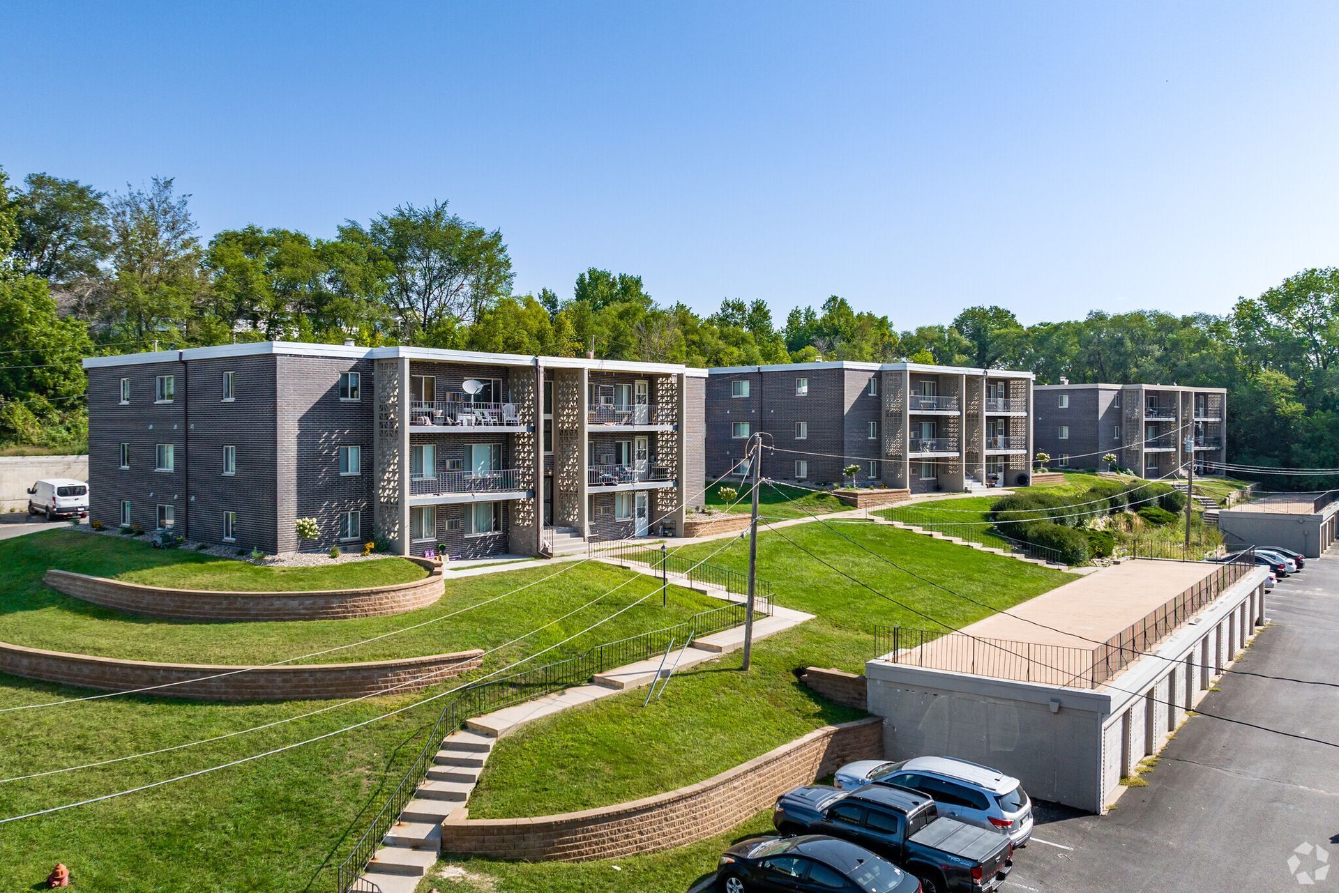 An aerial view of a large apartment building with cars parked in front of it.
