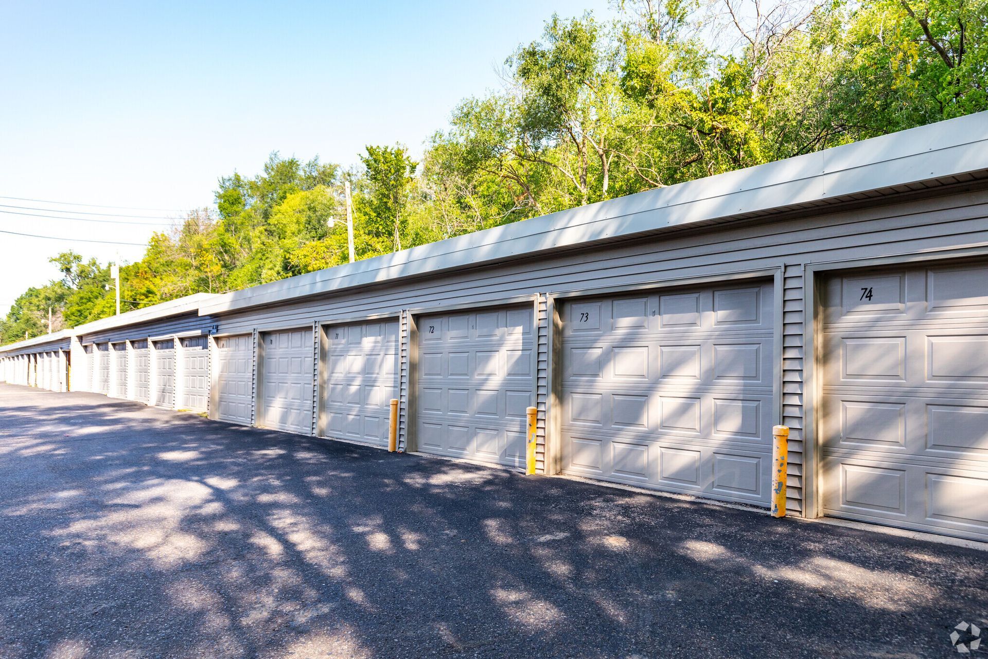 A row of garage doors with trees in the background