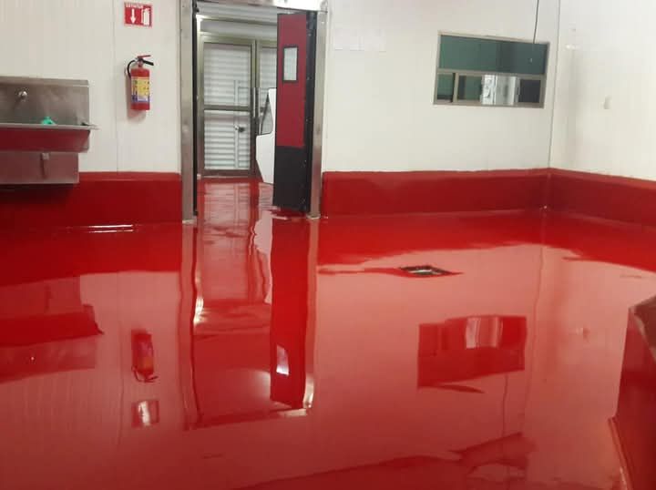 Uno stabile commerciale con il pavimento rosso in resina e un estintore sul muro.