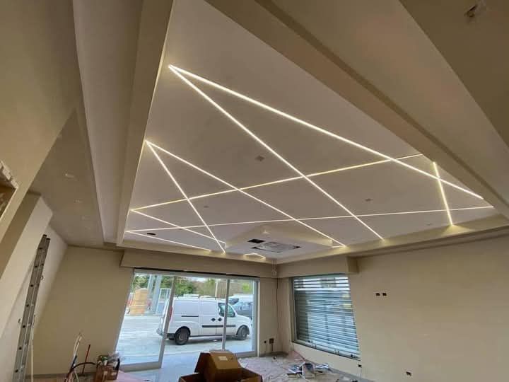 Un soggiorno con un soffitto in cartongesso decorato con motivi geometrici a LED.