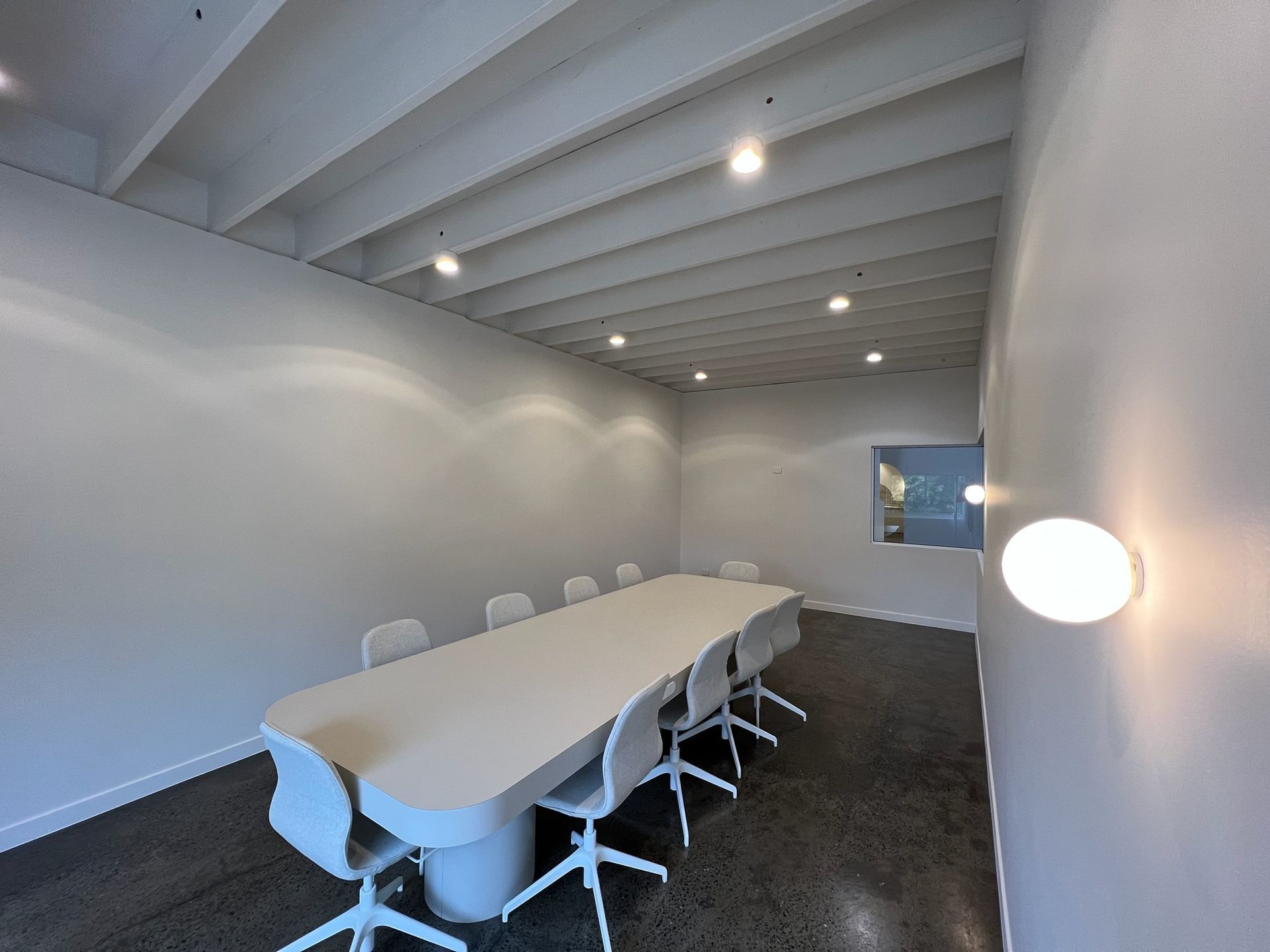 Modern conference room with a long table, white chairs, and recessed ceiling lights