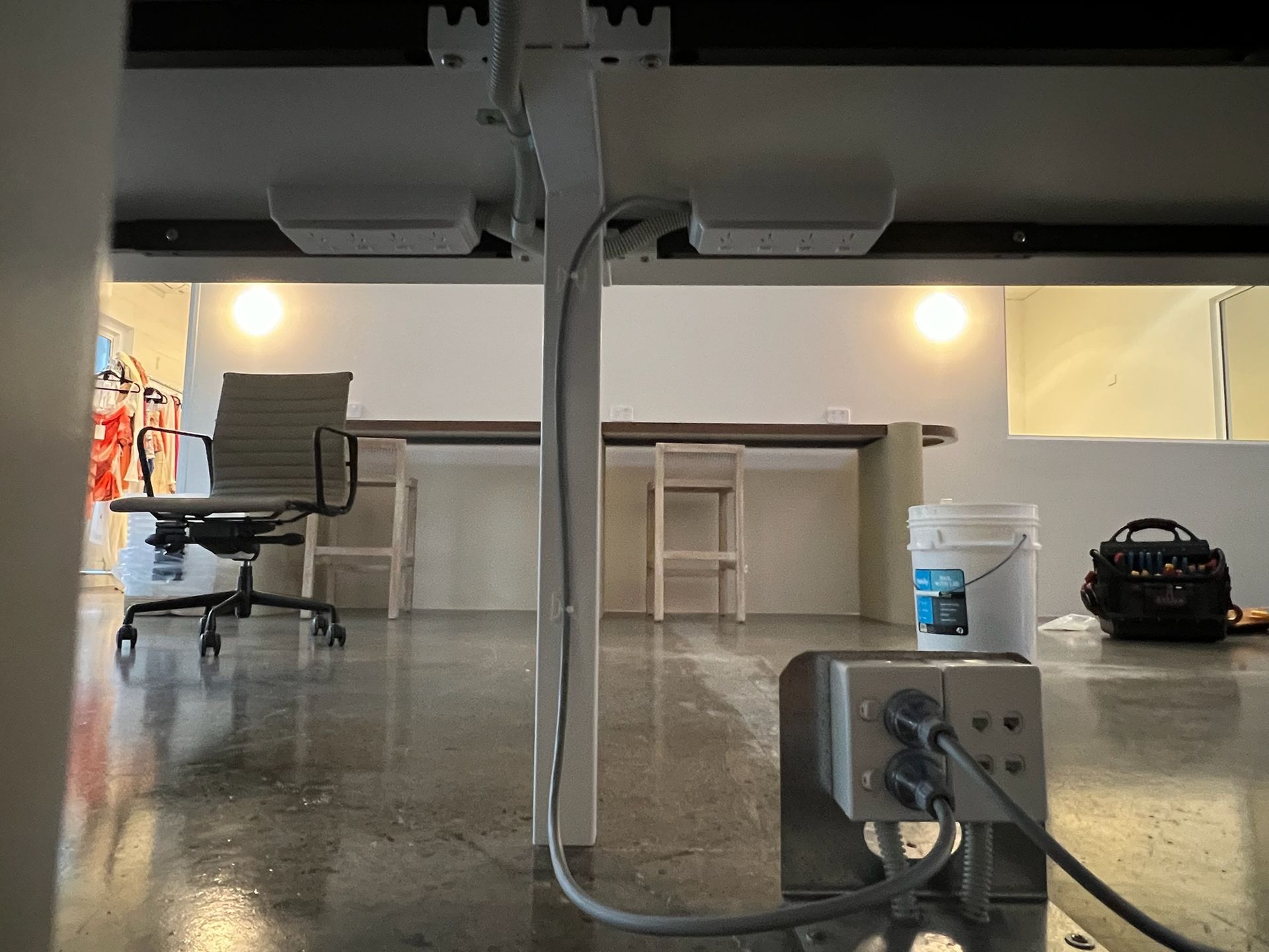 Empty office with desks, chairs, and a power outlet in the foreground, viewed from a low angle.