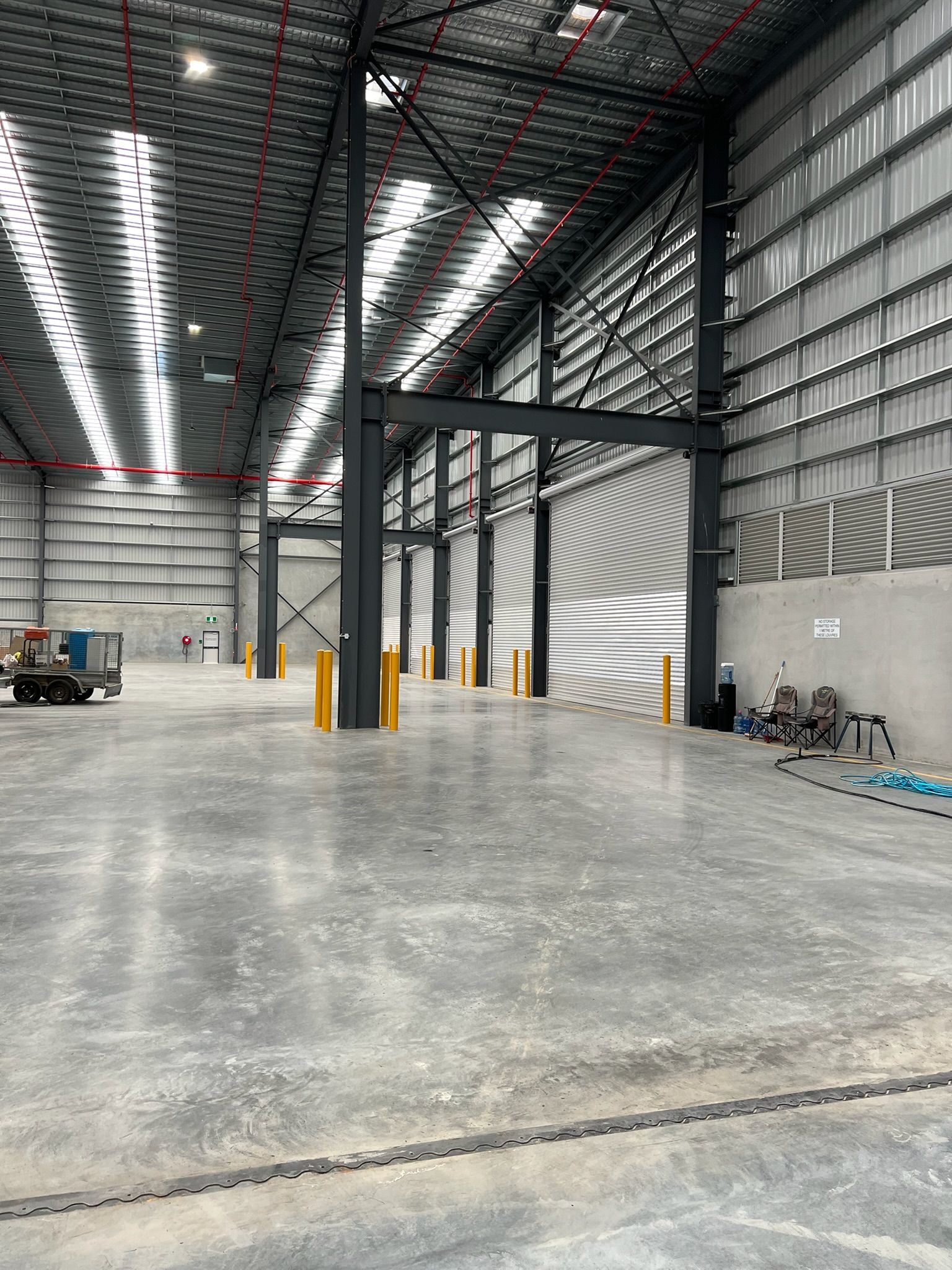 Empty industrial warehouse interior with high ceiling, concrete floor, and steel support columns