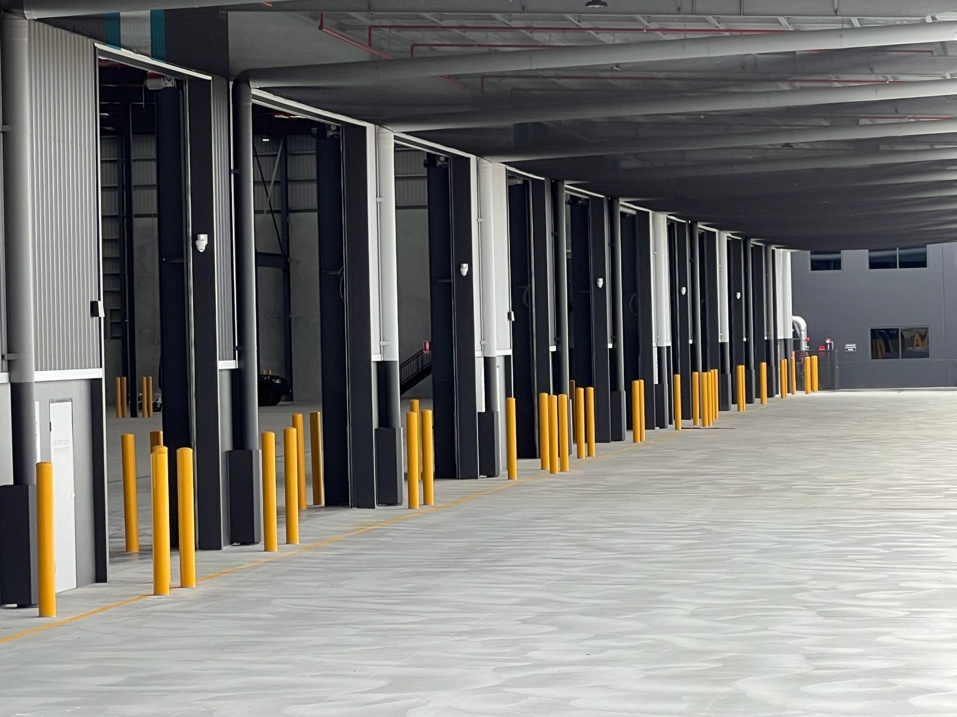 Empty warehouse loading dock with multiple bays and yellow safety bollards