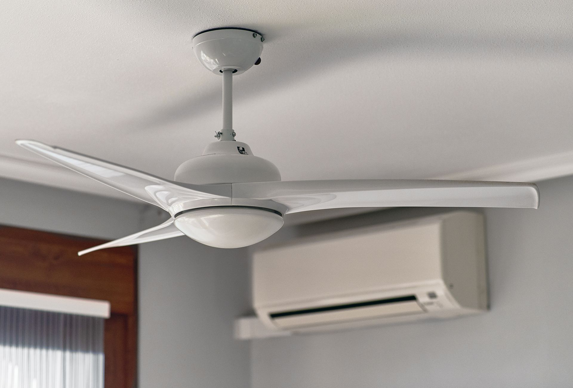 Ceiling fan and wall-mounted air conditioner in a room with a window blind