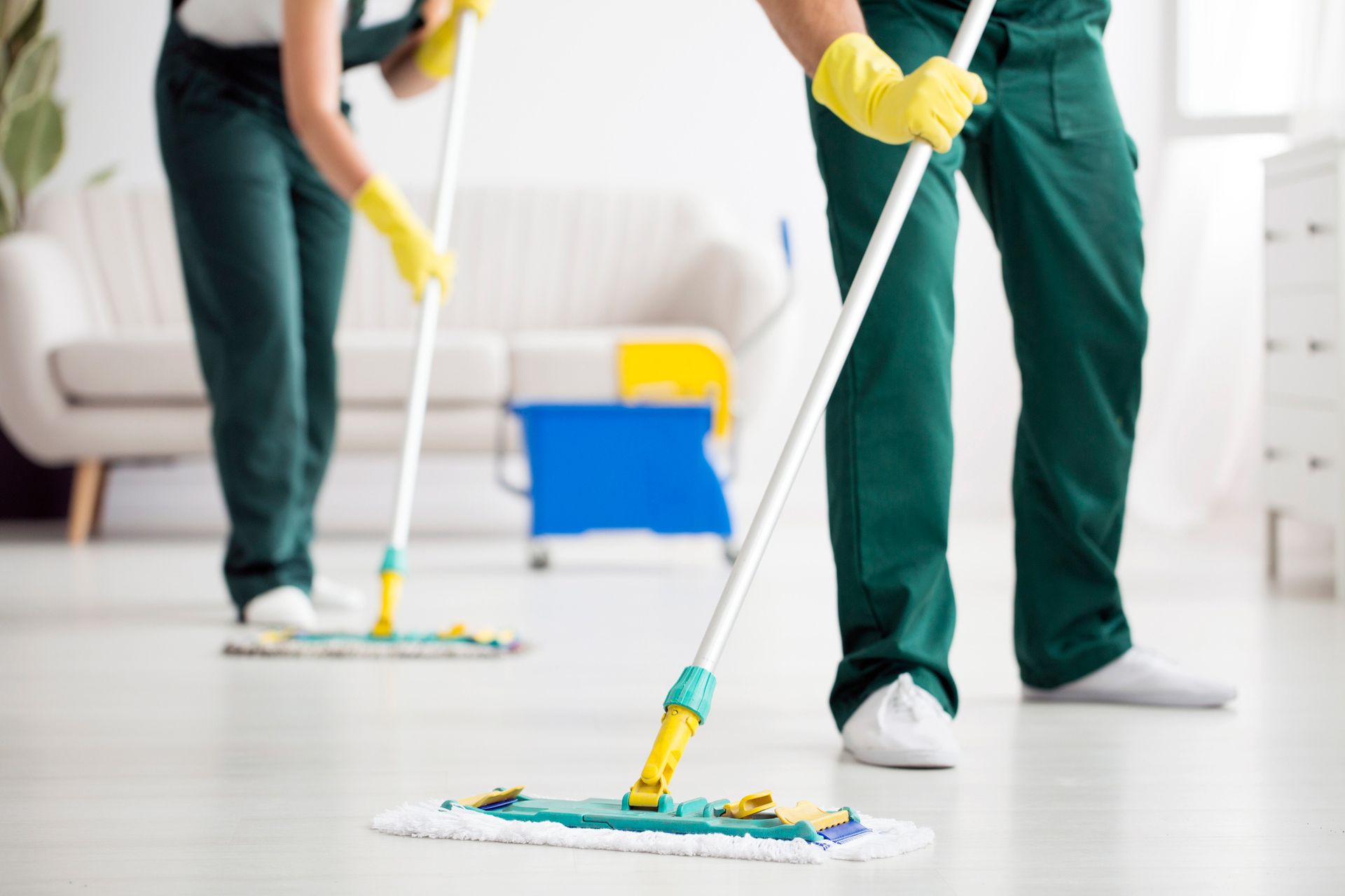 A man and a woman are mopping the floor in a living room.