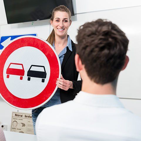 Driving Instructor Holding Street Signage — ABC Driving School in Central Coast NSW