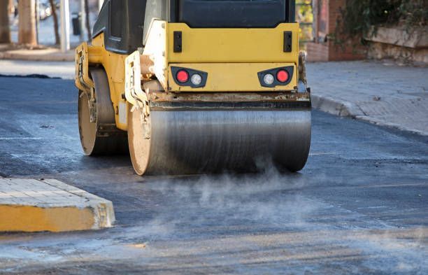 Road roller and asphalt paving machine at construction site.