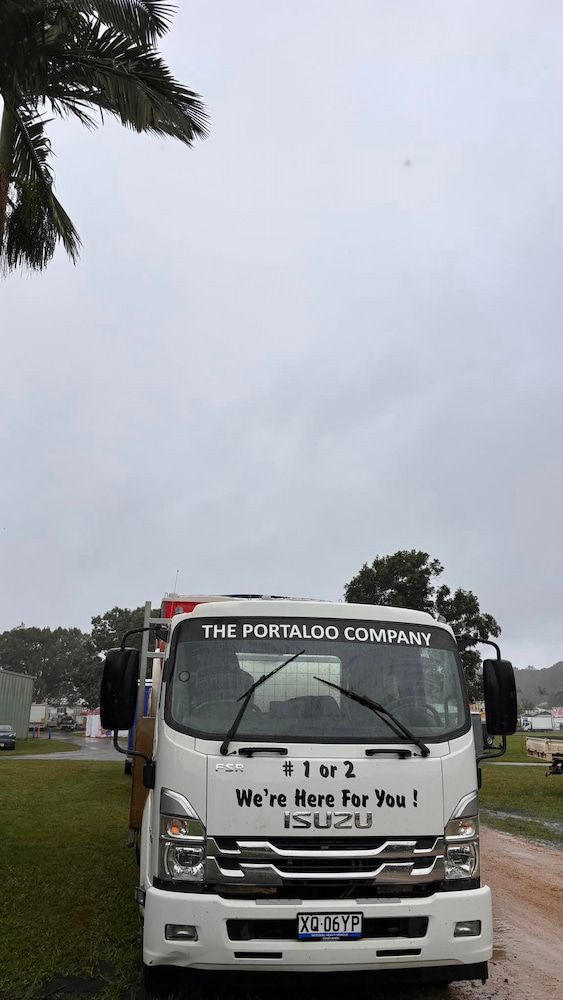 A White Truck Is Parked On The Side Of The Road Next To A Palm Tree — The Portaloo Co in Mareeba, QLD