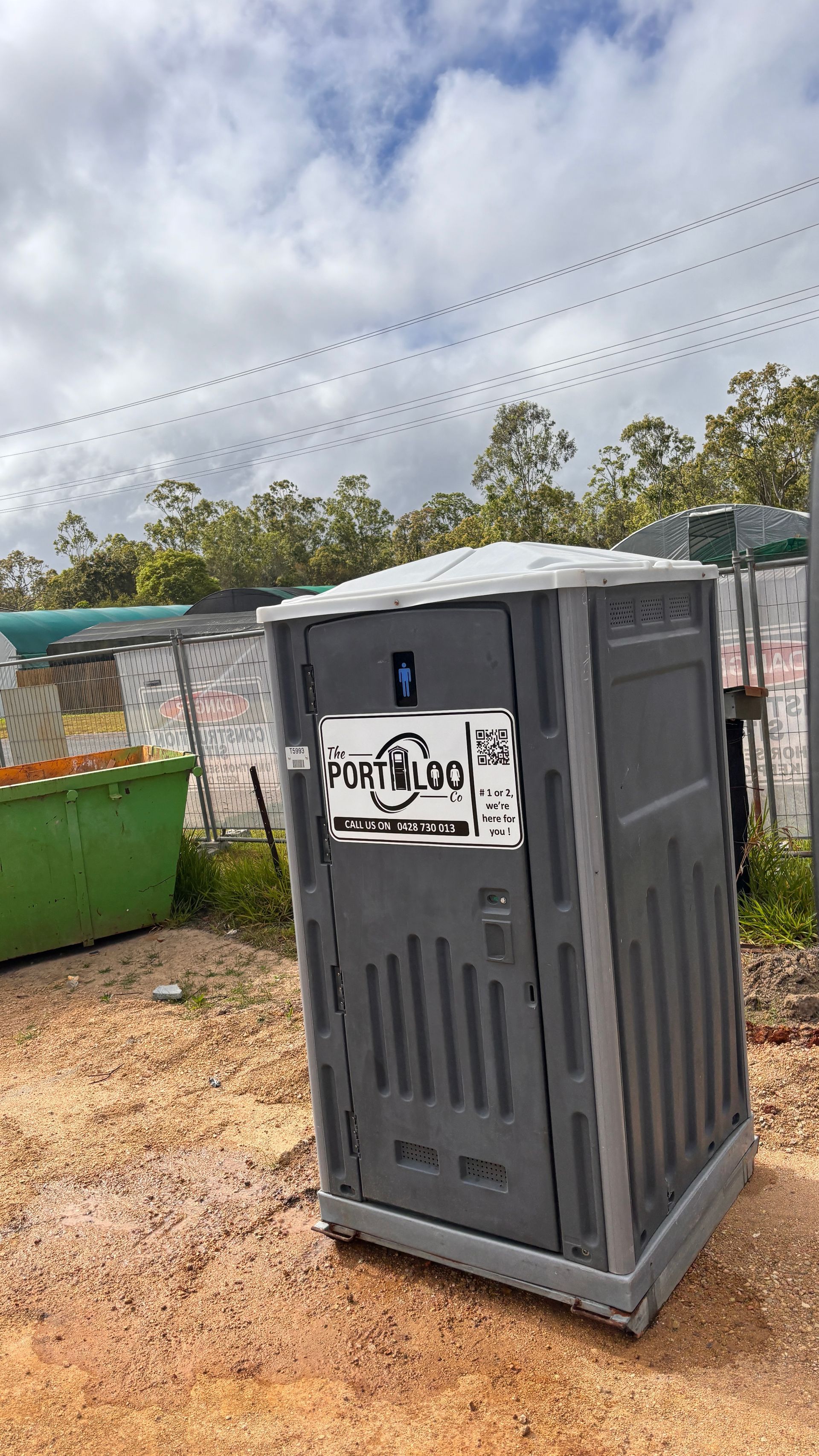 A Row Of Portable Toilets Are Lined Up In A Grassy Field — The Portaloo Co in Atherton, QLD
