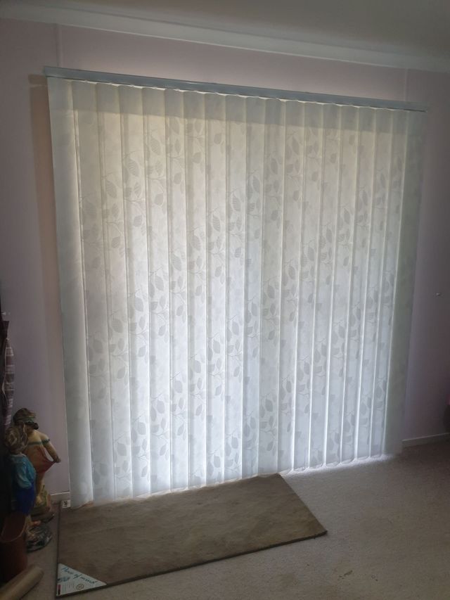 A Living Room With a Sliding Glass Door and White Vertical Blinds — BTS Blinds & Awnings in Gunnedah, NSW