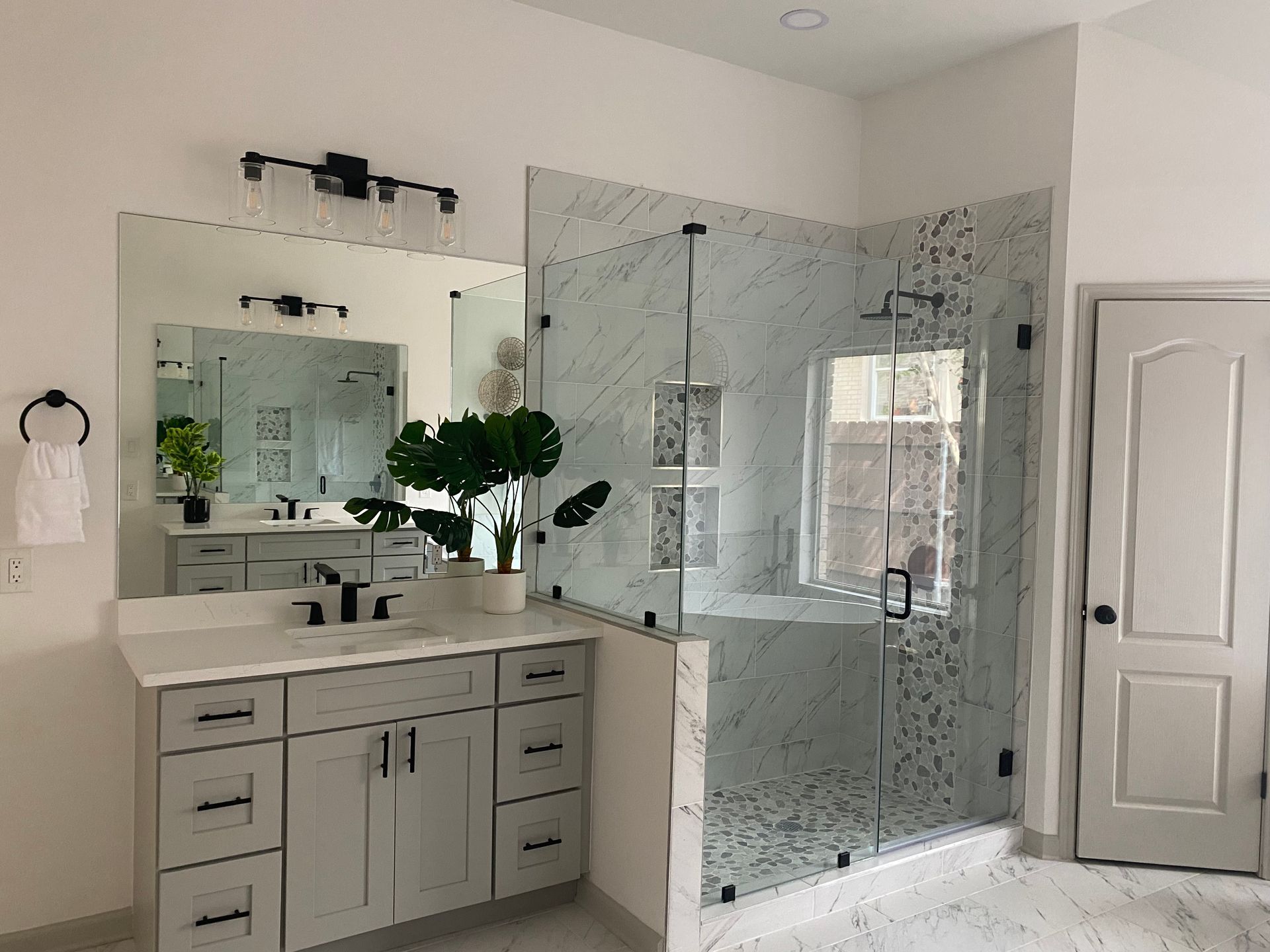 Luxurious bathroom with marble walls and glass shower, tub, and sauna.