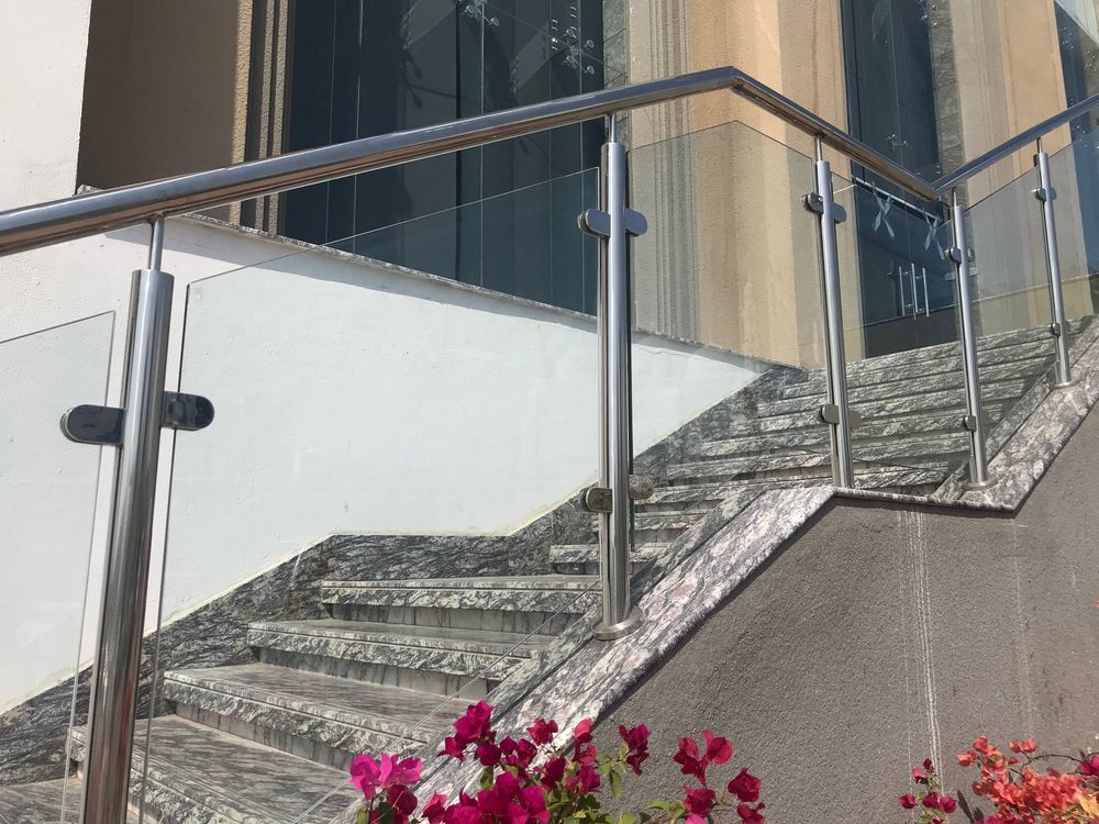 Staircase with stainless steel and glass railing; stone steps with pink flowers.
