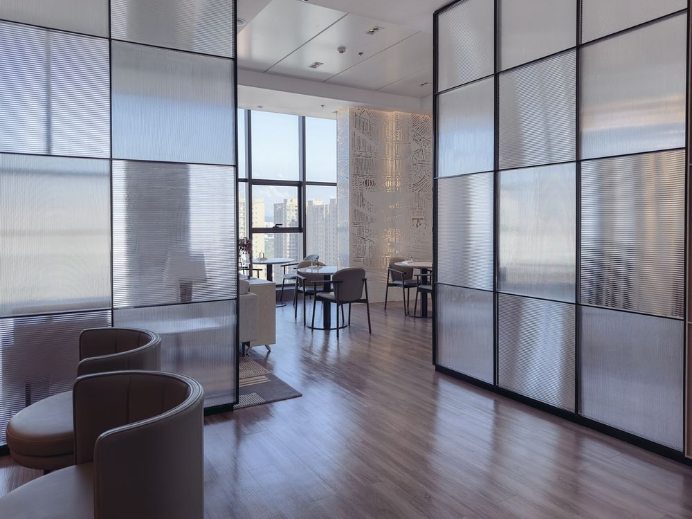 Elegant lounge area with frosted glass panel walls and modern furniture, with a city view.
