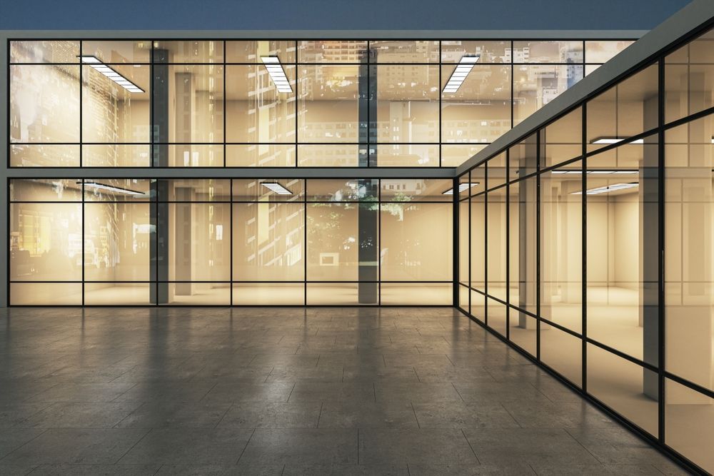 Empty modern building with large glass windows reflecting city lights.