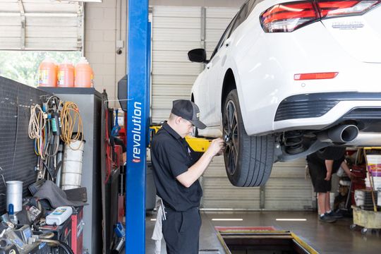 A white truck is sitting on a lift in a garage.