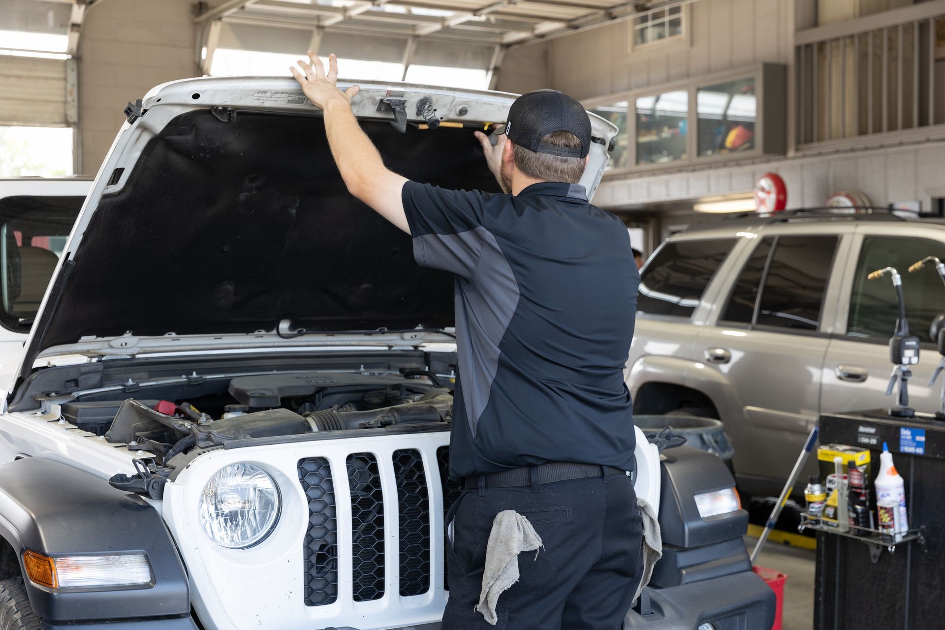 A man with a beard is working on the engine of a car.