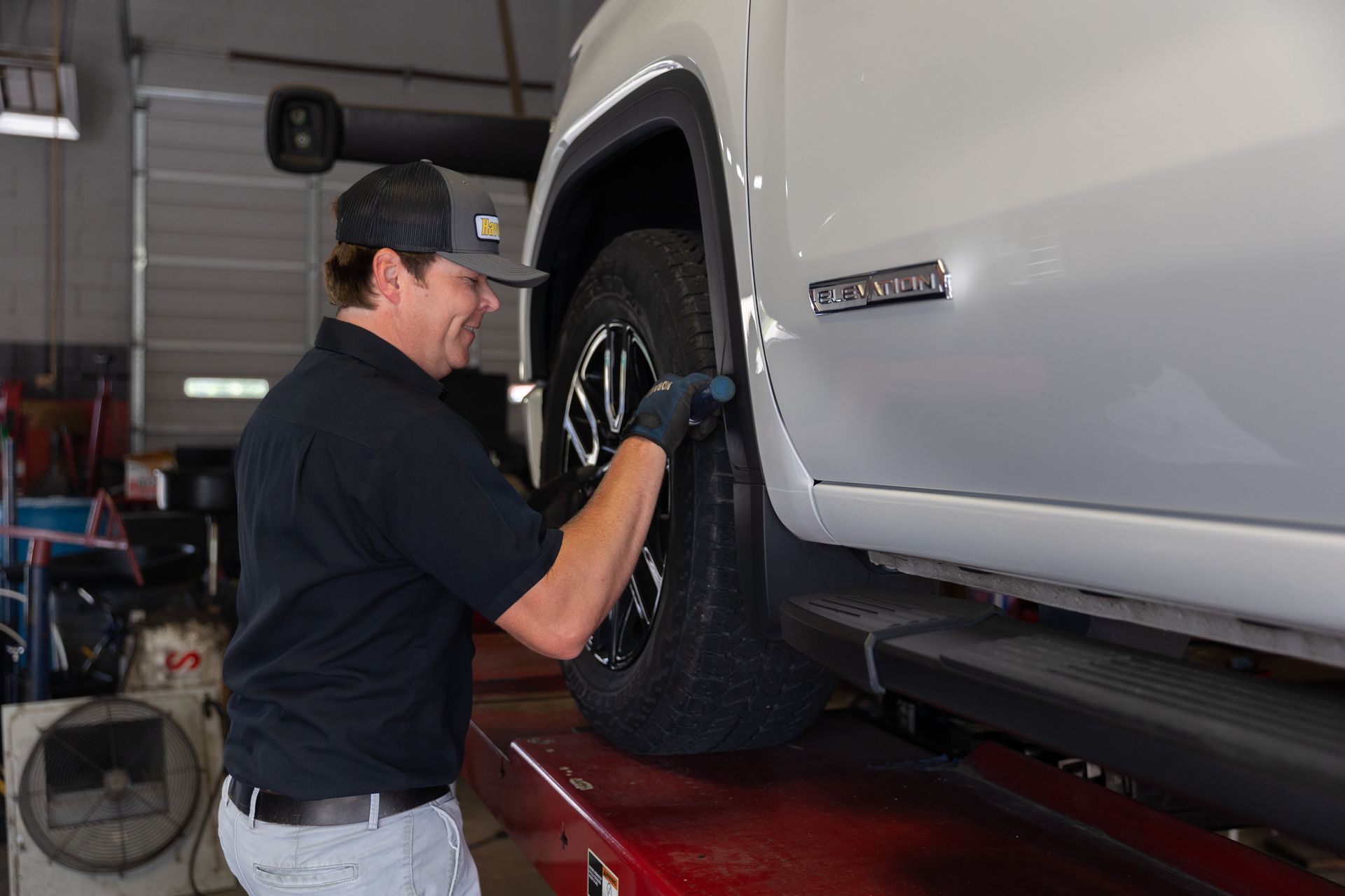 A man is adjusting a tire on a truck in a garage.